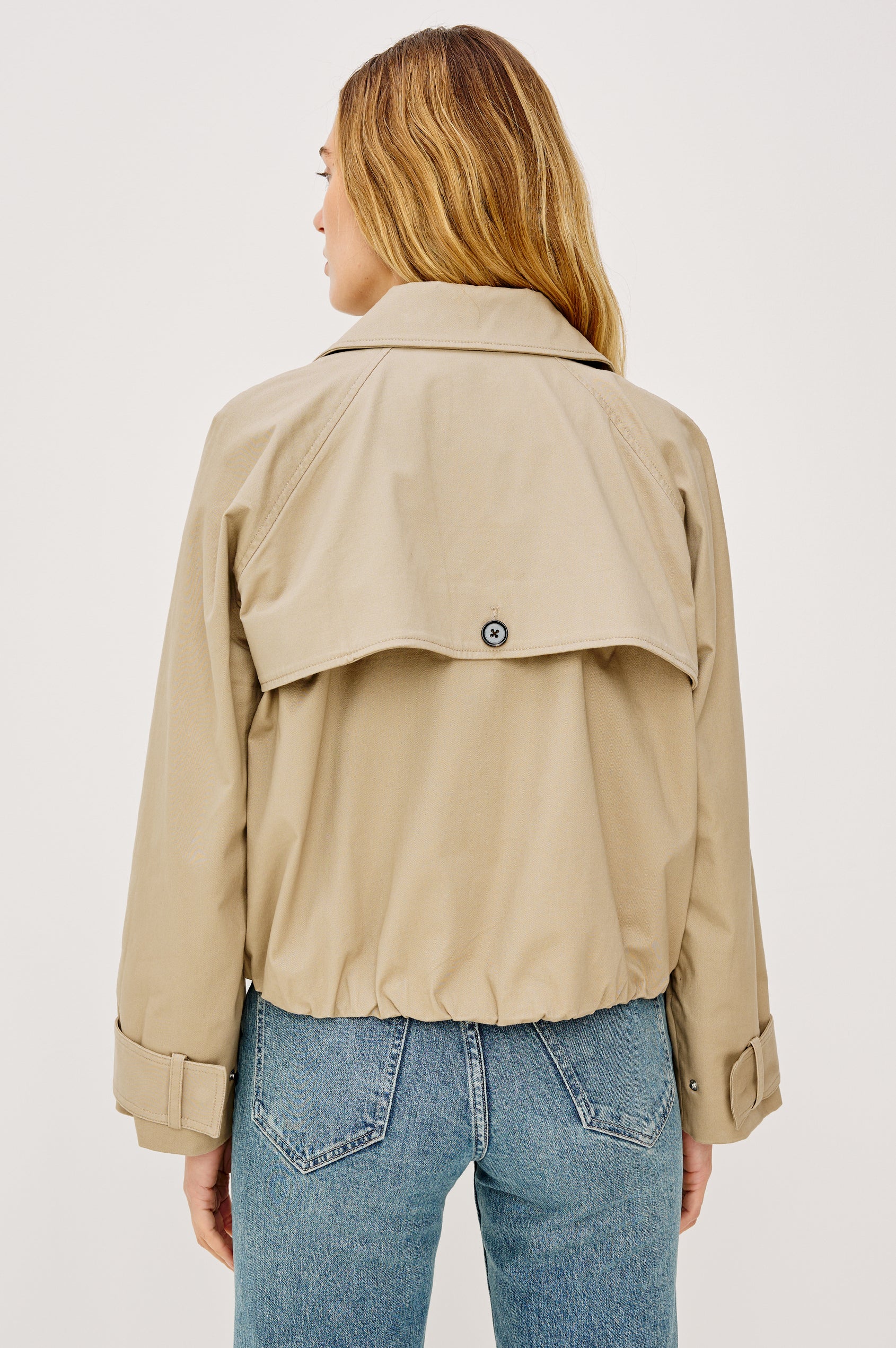 Jett Double Breasted, Cropped Trench Jacket, Lapel, Adjustable Cuff Belt, Side Pockets and Elasticated Hem in Taupe Colorway. Back View Featured on Model.