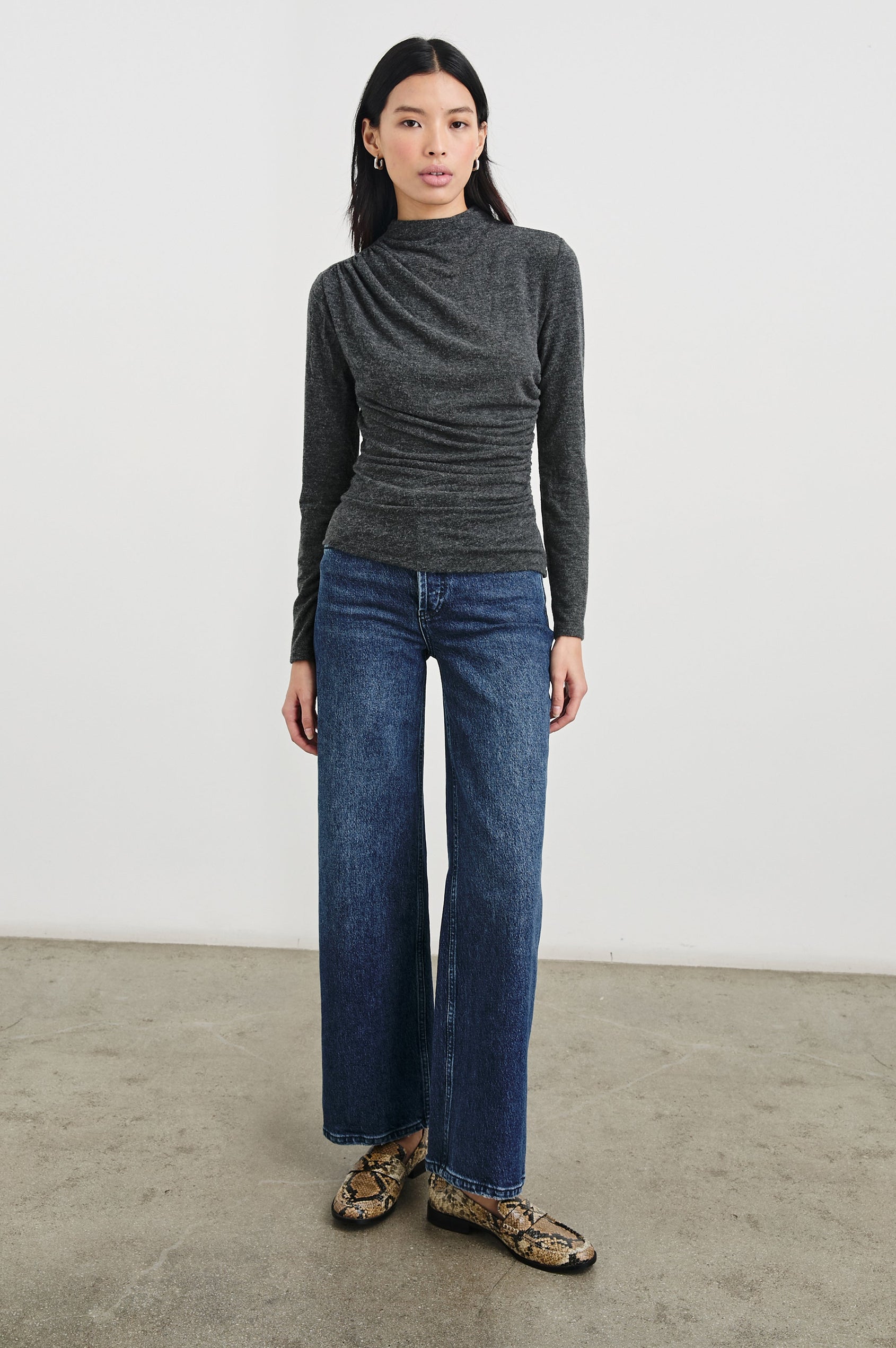 Joelle Long Sleeve Top with An Asymmetrical Mock Neck and Shirring on the Right Shoulder in Charcoal Colorway - Front Full Body View Featured on Model