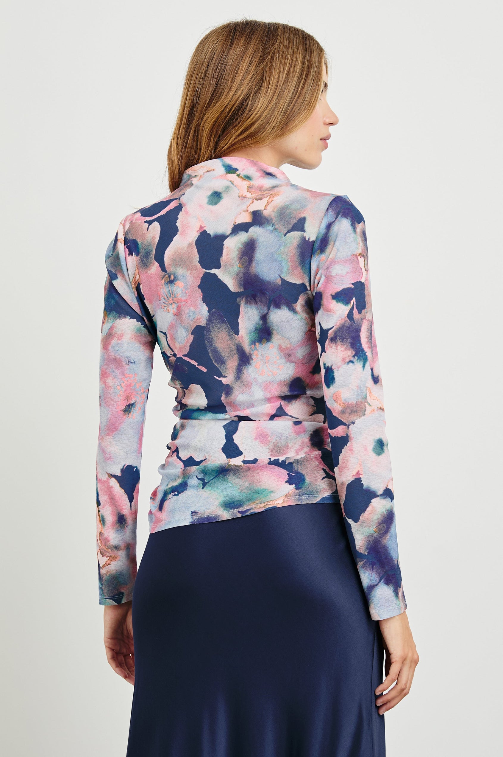 Joelle Long Sleeve Top with An Asymmetrical Mock Neck and Shirring on the Right Shoulder in Midnight Verbena Colorway, with slightly abstract flowers in pinks, purples, blues and oranges on Midnight - Back View Featured on Model