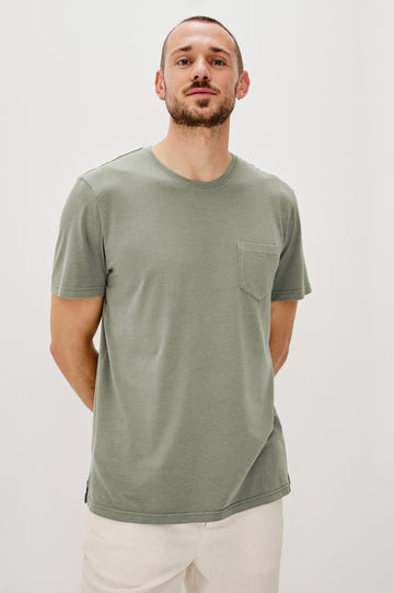 Johnny Short Sleeve T-Shirt with a Crew Neck, Chest Patch Pocket and Small Slits at the Side Hems in Olive Colorway - Front View Featured on Model