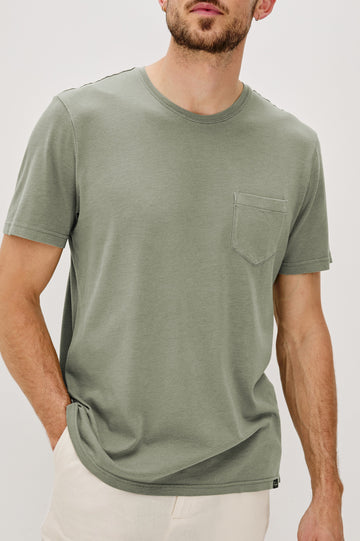 Johnny Short Sleeve T-Shirt with a Crew Neck, Chest Patch Pocket and Small Slits at the Side Hems in Olive Colorway - Front Detail View Featured on Model
