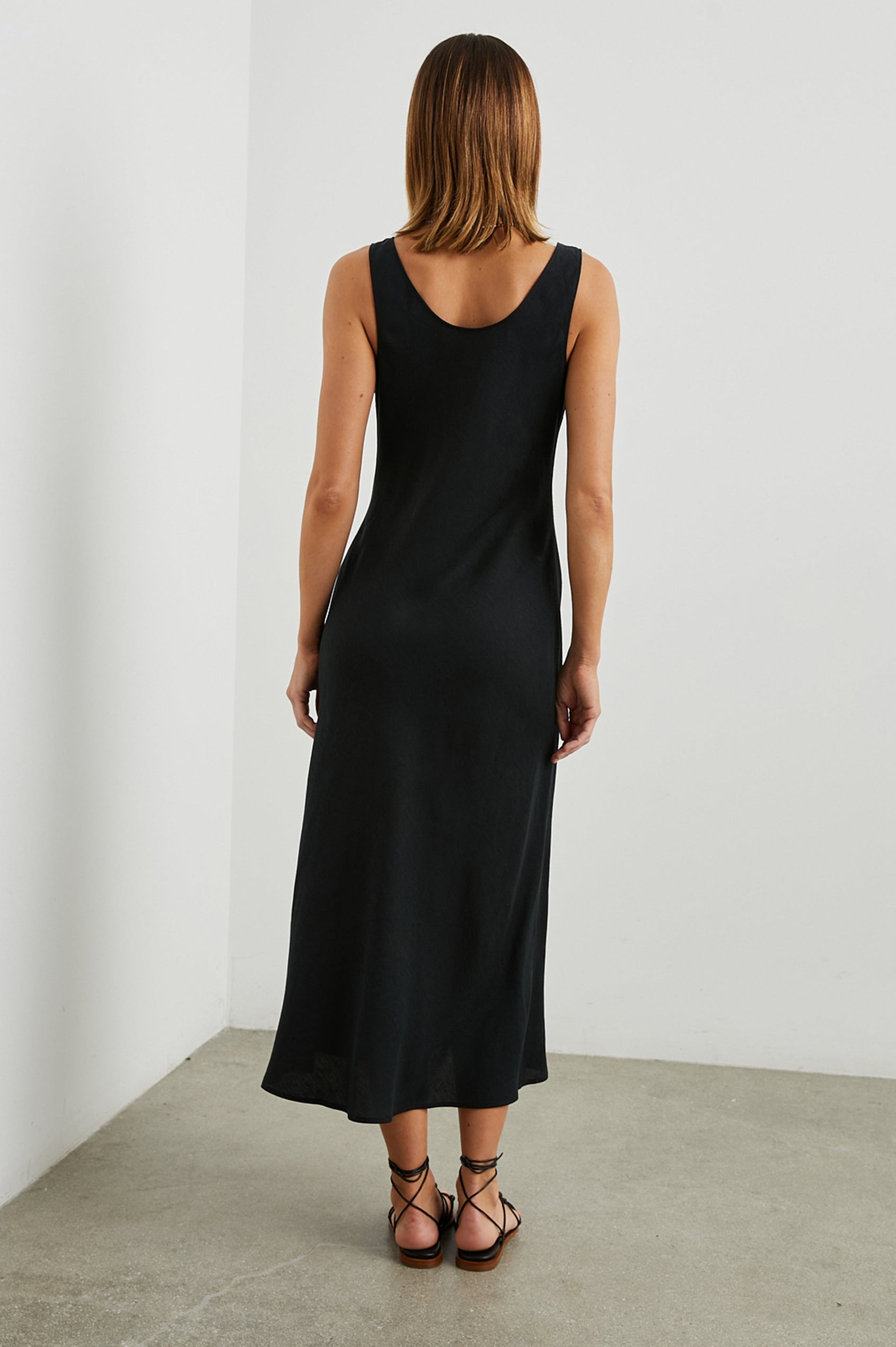 Kailani Sleeveless Midi Dress with Shoulder Straps, a Scoop Neck and Side Slit to the Knee in Black Colorway - Back Full Body View Featured on Model