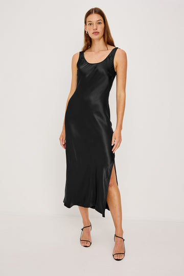 Kailani Sleeveless Midi Dress with Shoulder Straps, a Scoop Neck and Side Slit to the Knee in Black Satin Crepe Colorway - Front Full Body View Featured on Model