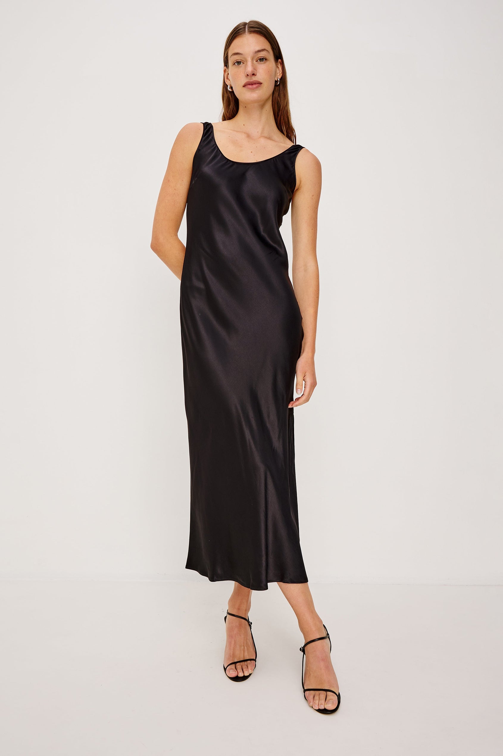 Kailani Sleeveless Midi Dress with Shoulder Straps, a Scoop Neck and Side Slit to the Knee in Black Satin Crepe Colorway - Front Full Body View Featured on Model