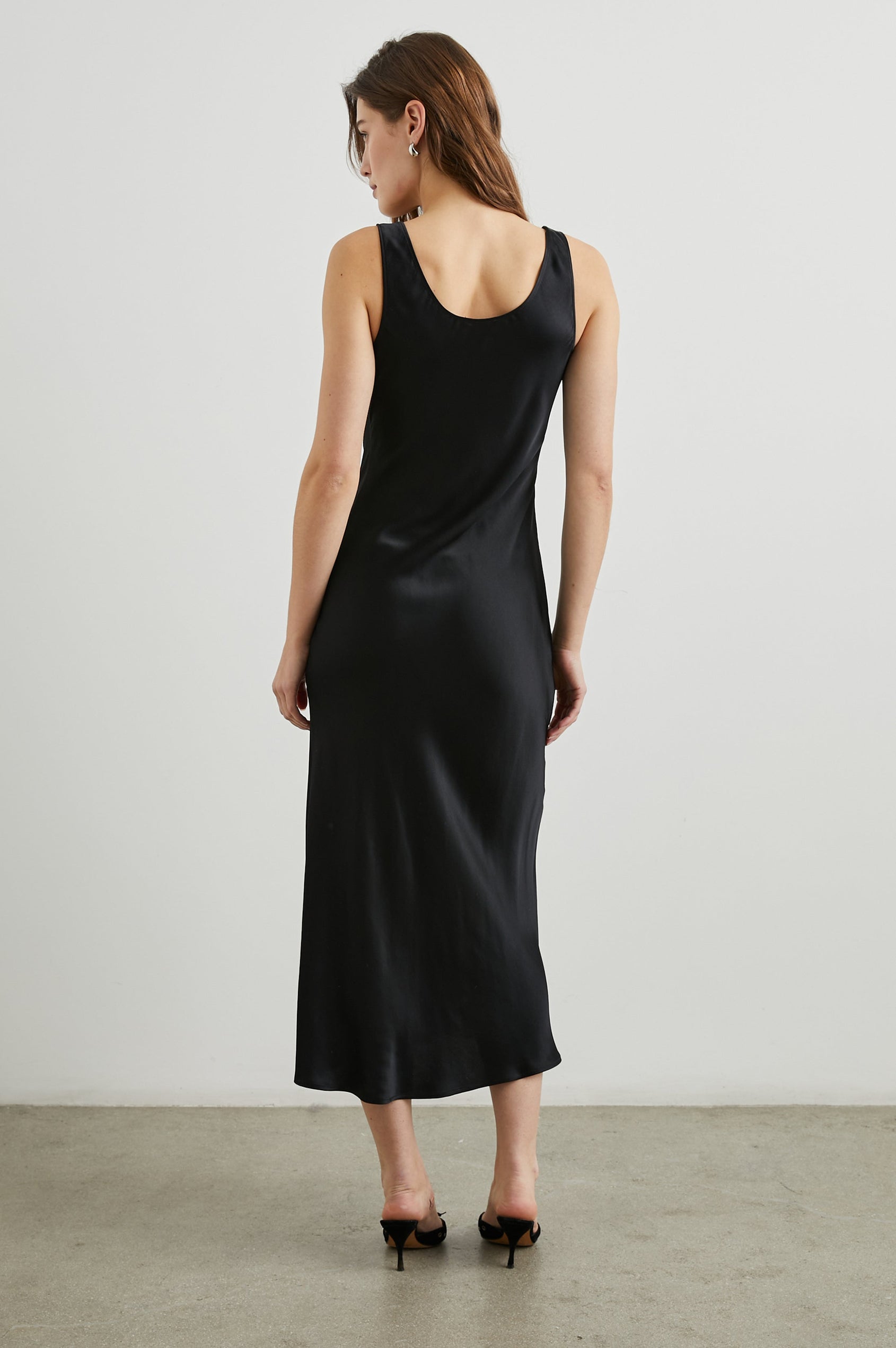 Kailani Sleeveless Midi Dress with Shoulder Straps, a Scoop Neck and Side Slit to the Knee in Black Satin Crepe Colorway - Back Full Body View Featured on Model