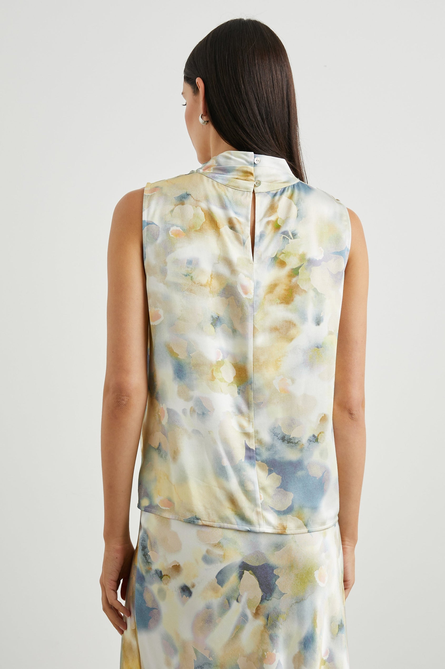 Kaleen Sleeveless Top with Mock Neck with Buttons and Keyhole on the Back and Draped Fabric on the Upper Chest in Diffused Blossom Colorway, in creams, yellows and blues - Back View Featured on Model