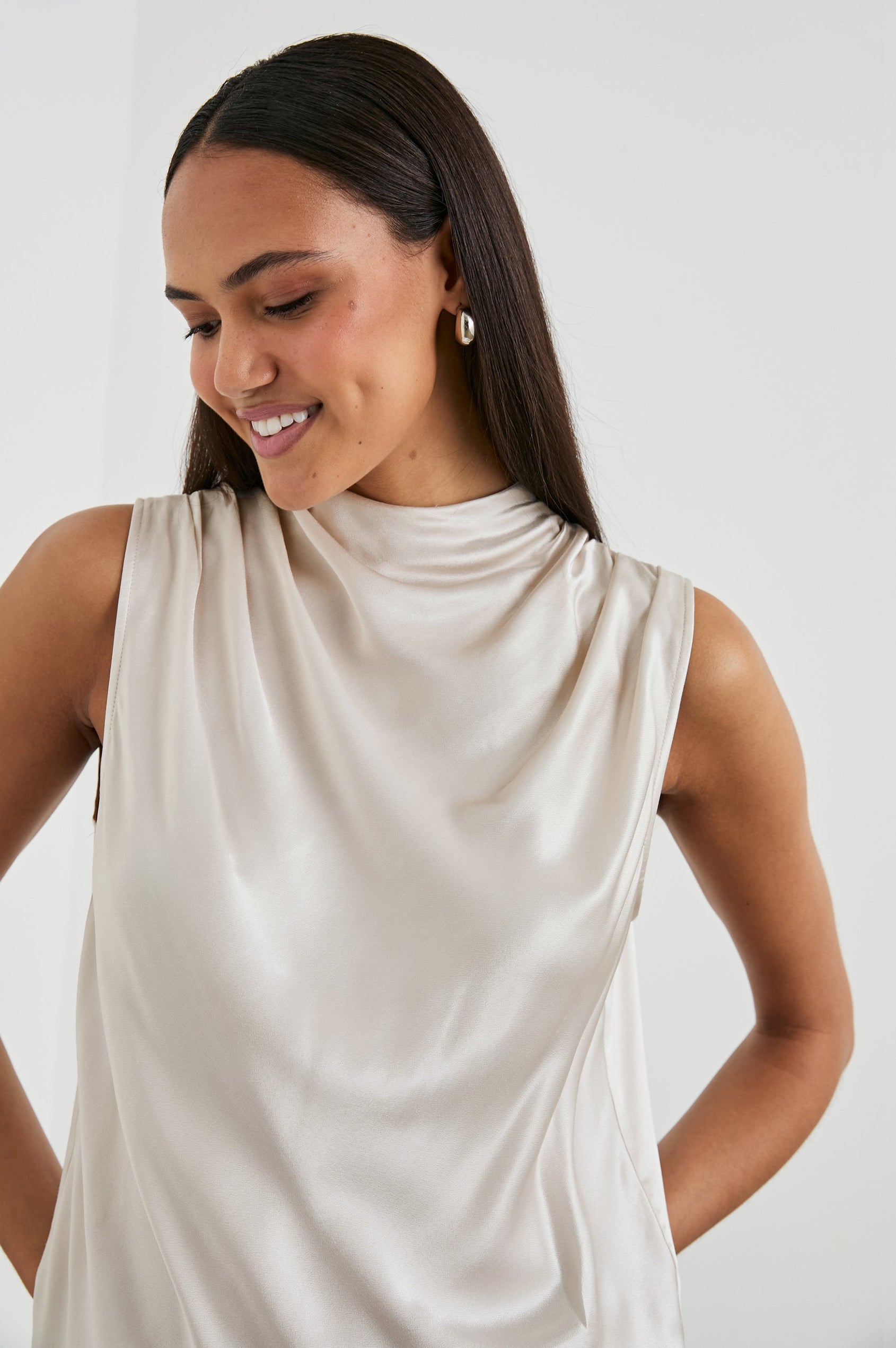 Kaleen Sleeveless Top with Mock Neck with Buttons and Keyhole on the Back and Draped Fabric on the Upper Chest in Ivory Colorway- Front View Featured on Model