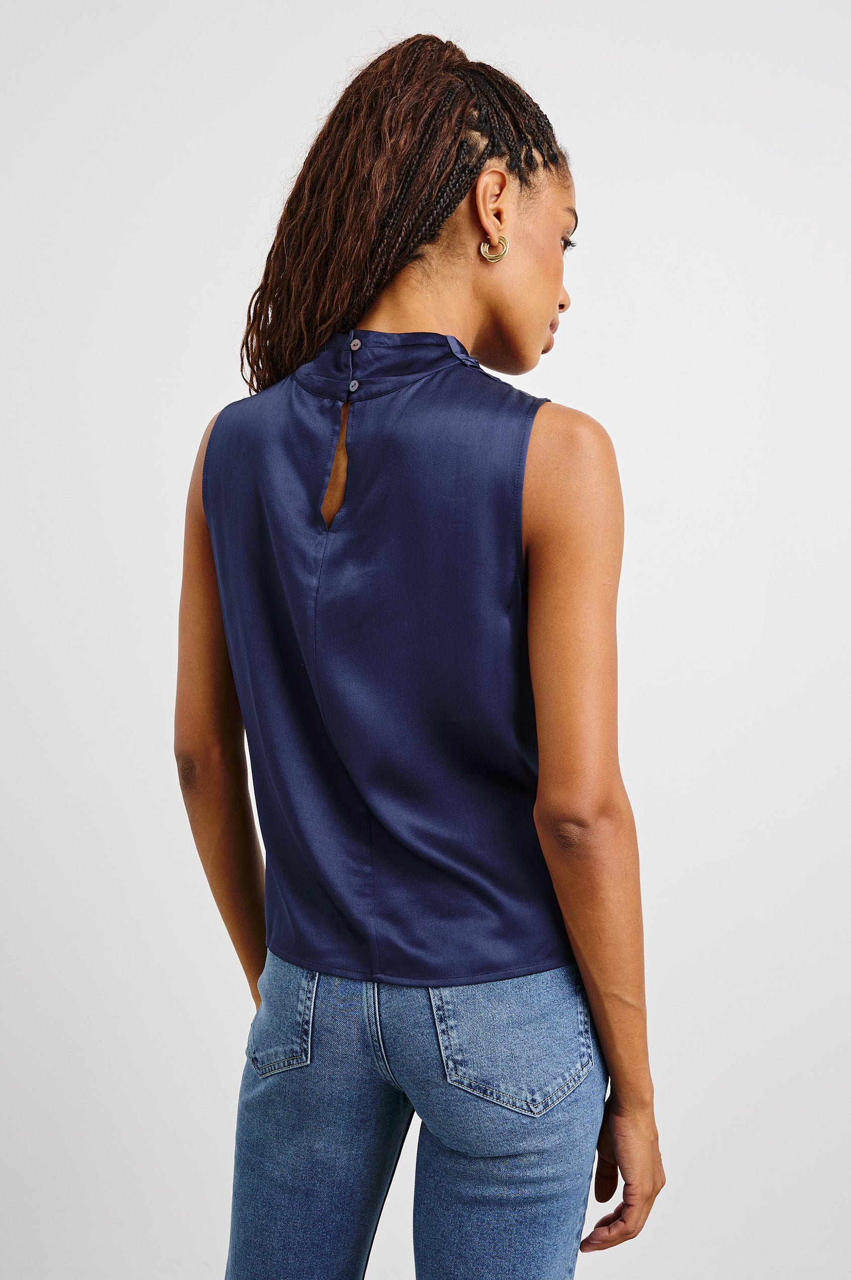 Kaleen Sleeveless Top with Mock Neck with Buttons and Keyhole on the Back and Draped Fabric on the Upper Chest in Navy Colorway - Back View Featured on Model