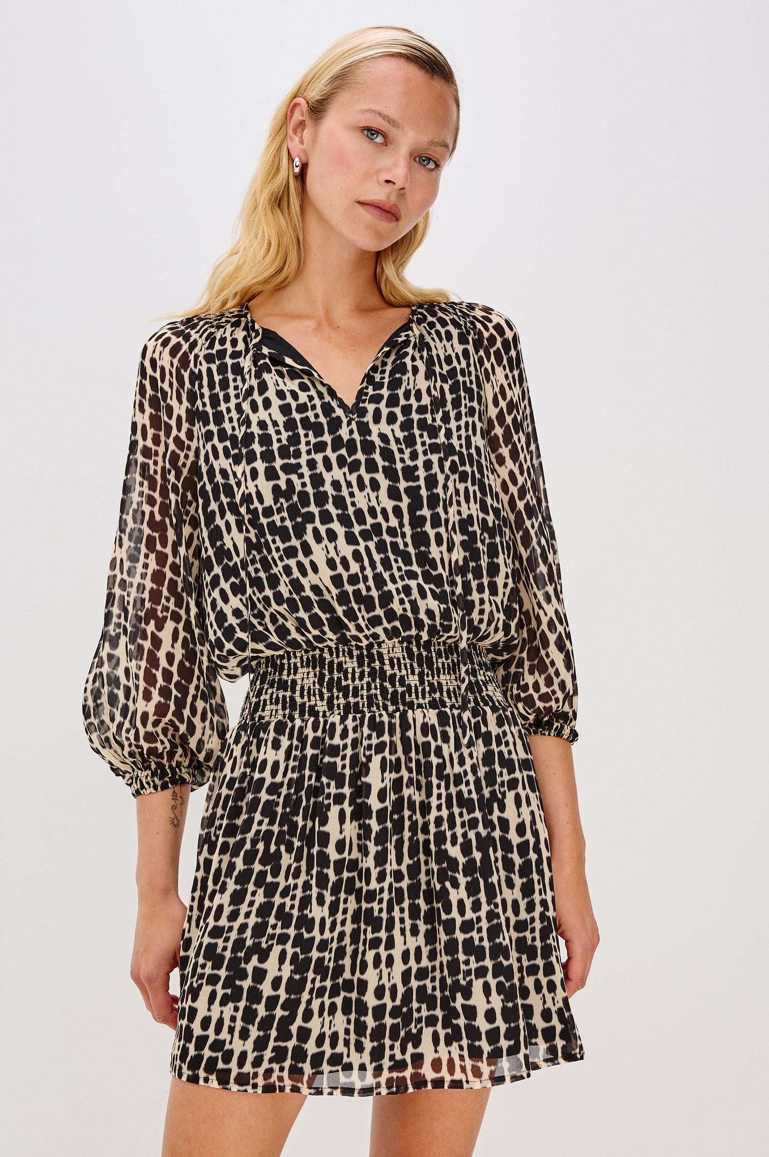 Printed dress with a tiered skirt and smocked detailing at the shoulders and waist. The dress includes a front tie closure for an adjustable neckline. Front View on Model.