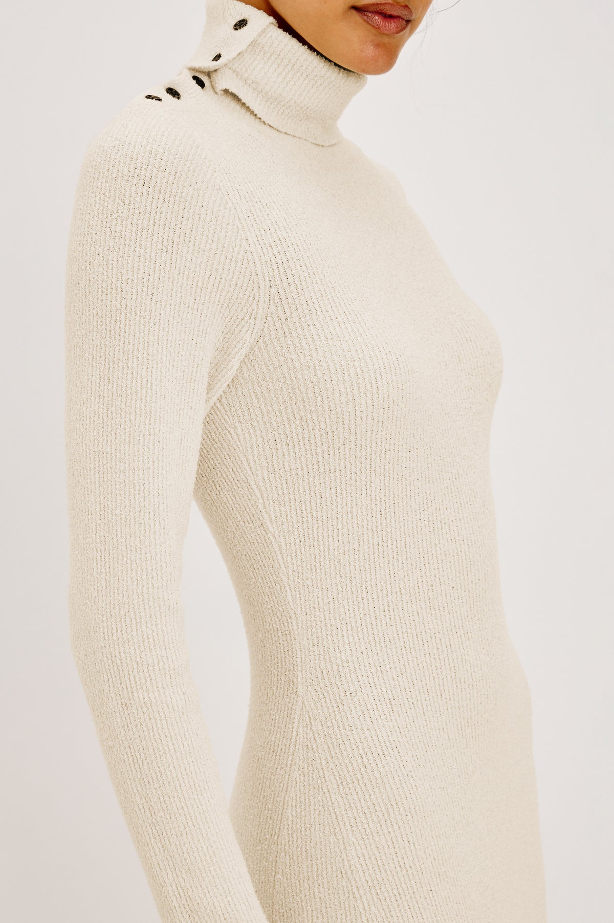 Kat Maxi Dress in Ribbed Cotton Blend With Foldover Turtleneck Button Neckline, Long Sleeves, Fitted Silhouette, Long Sleeves, Side Placket, and Subtle Flare at Hem in Ivory Colorway - Side Detail Crop View Featured on Model