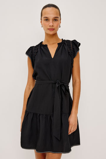 Katia Mini Dress in Textured Poplin With Shirring, Lace, and Ruffle Trim at Shoulders, Flutter Sleeves With Contrast Stitching, Adjustable Belted Ties, and Fully Lined Skirt in Black Colorway - Upper Body Front View Featured on Model