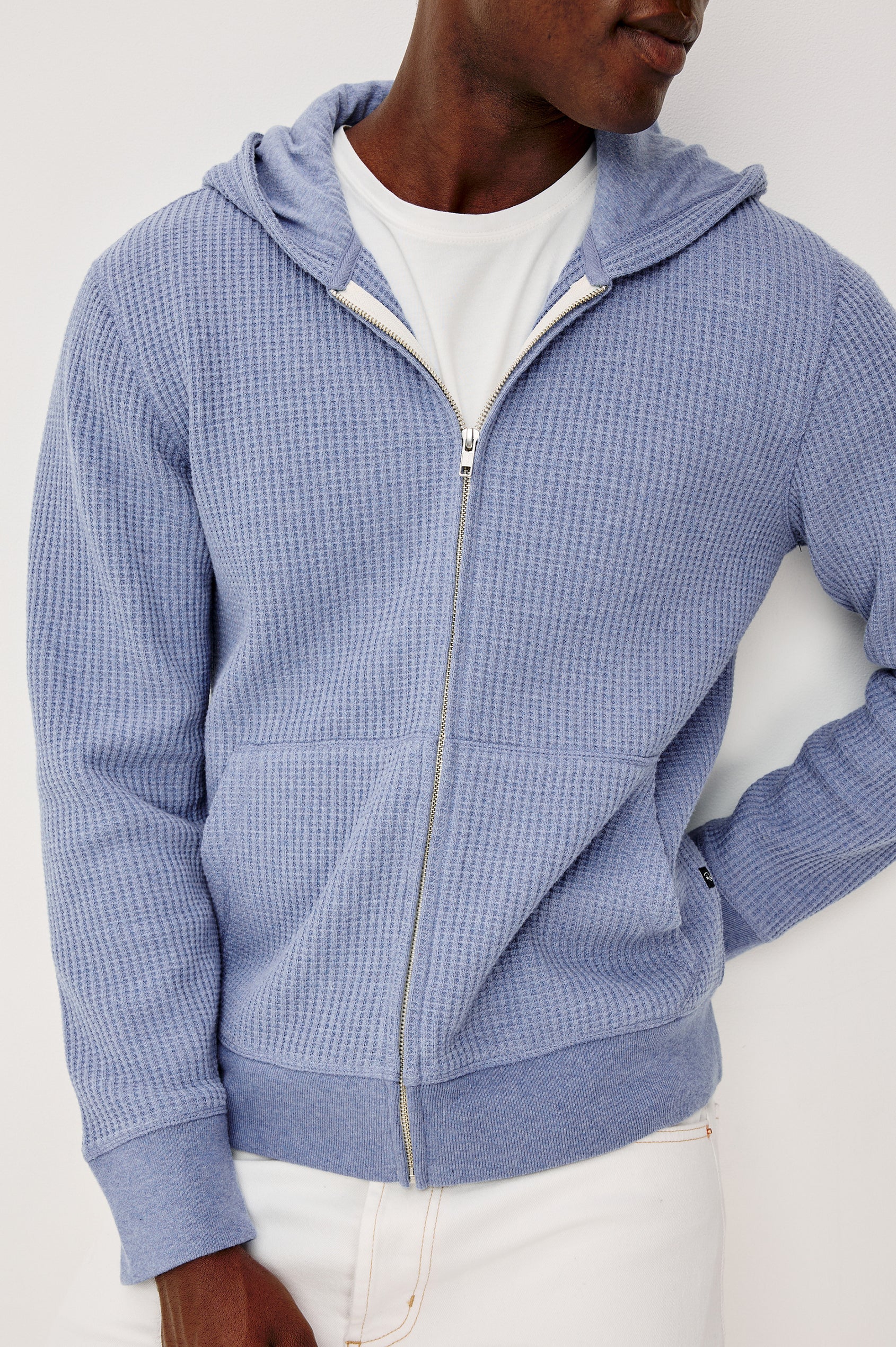 Kenton is a zip front hooded sweatshirt with front patch pockets and ribbed cuffs in Blue Heather colorway. Front detailed view featured on model.