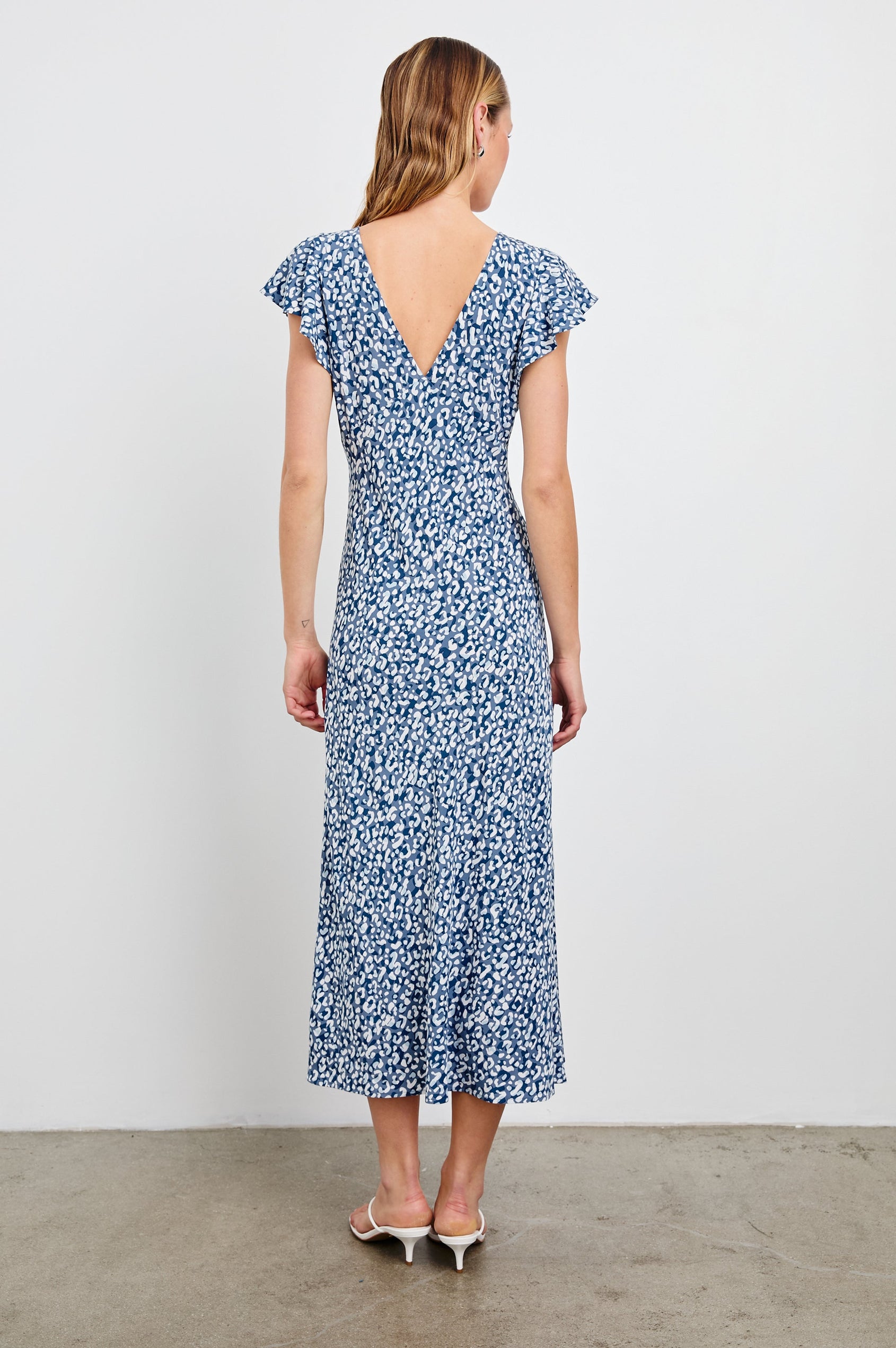 Kenz Midi Dress with Flutter cap Sleeves, and a deep V Neck in Blue Mixed Cheetah Colorway, Spots in Blues and White - Back Full Body View Featured on Model