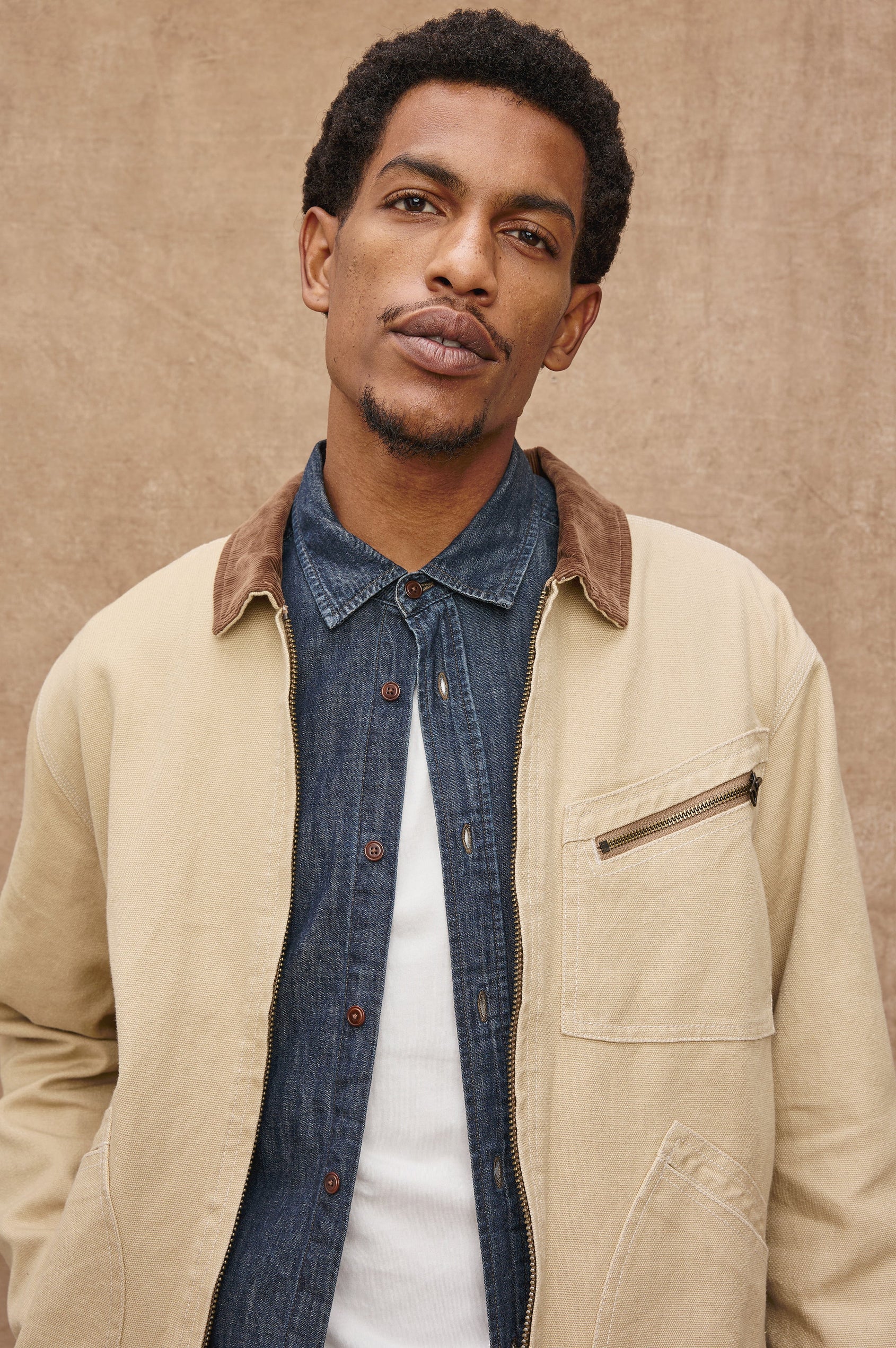 Ketter Zip Up Jacket with Two Curved Front Patch Pockets, a Diagonally Zippered Chest Patch Pocket and Adjustable Button Straps on the Hem in Duck Colorway, a Tan with a Darker Brown Collar - Front Detail View Featured on Model