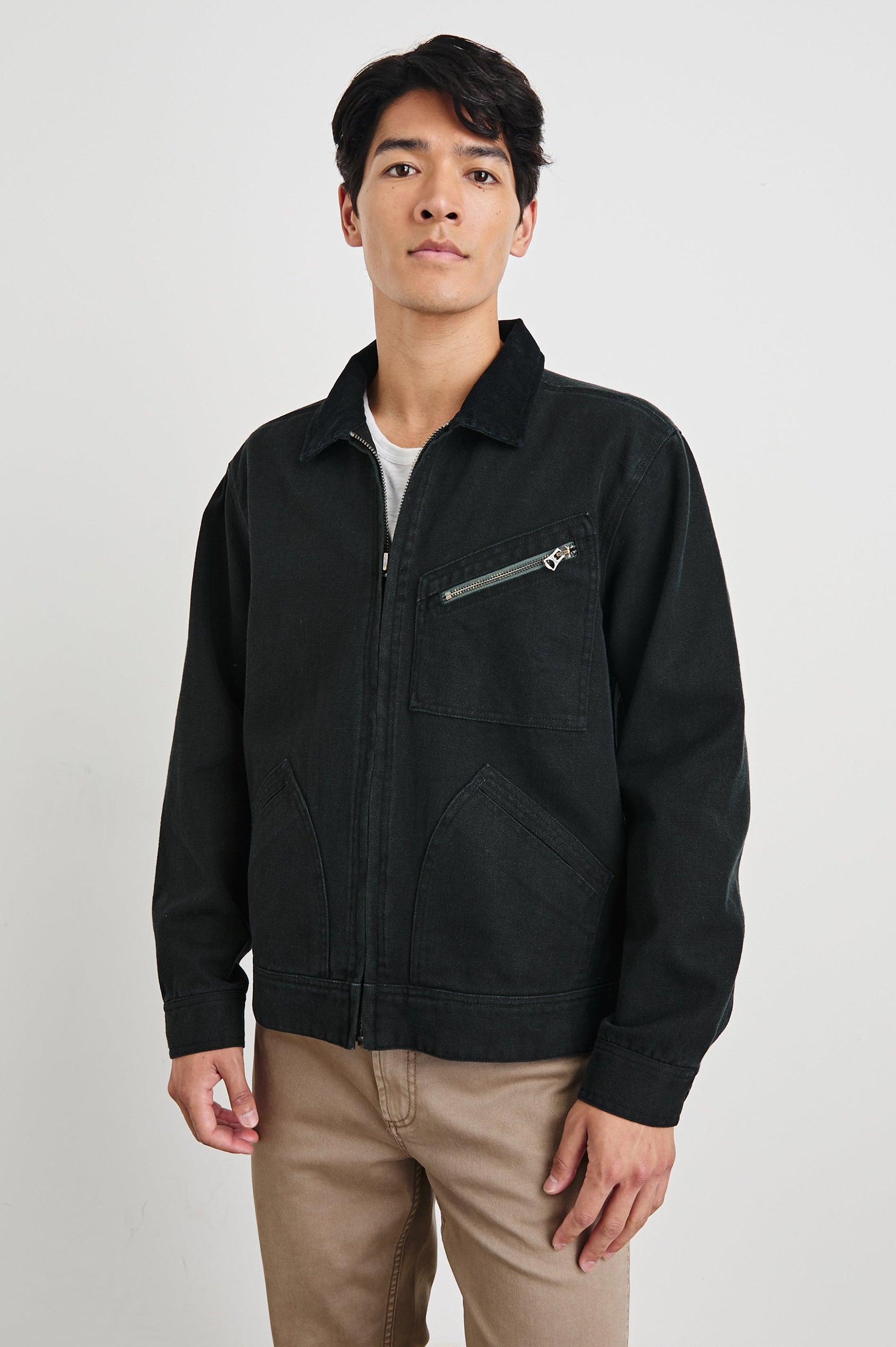 Ketter Zip Up Jacket with Two Curved Front Patch Pockets, a Diagonally Zippered Chest Patch Pocket and Adjustable Button Straps on the Hem in Raven Colorway - Front View Featured on Model