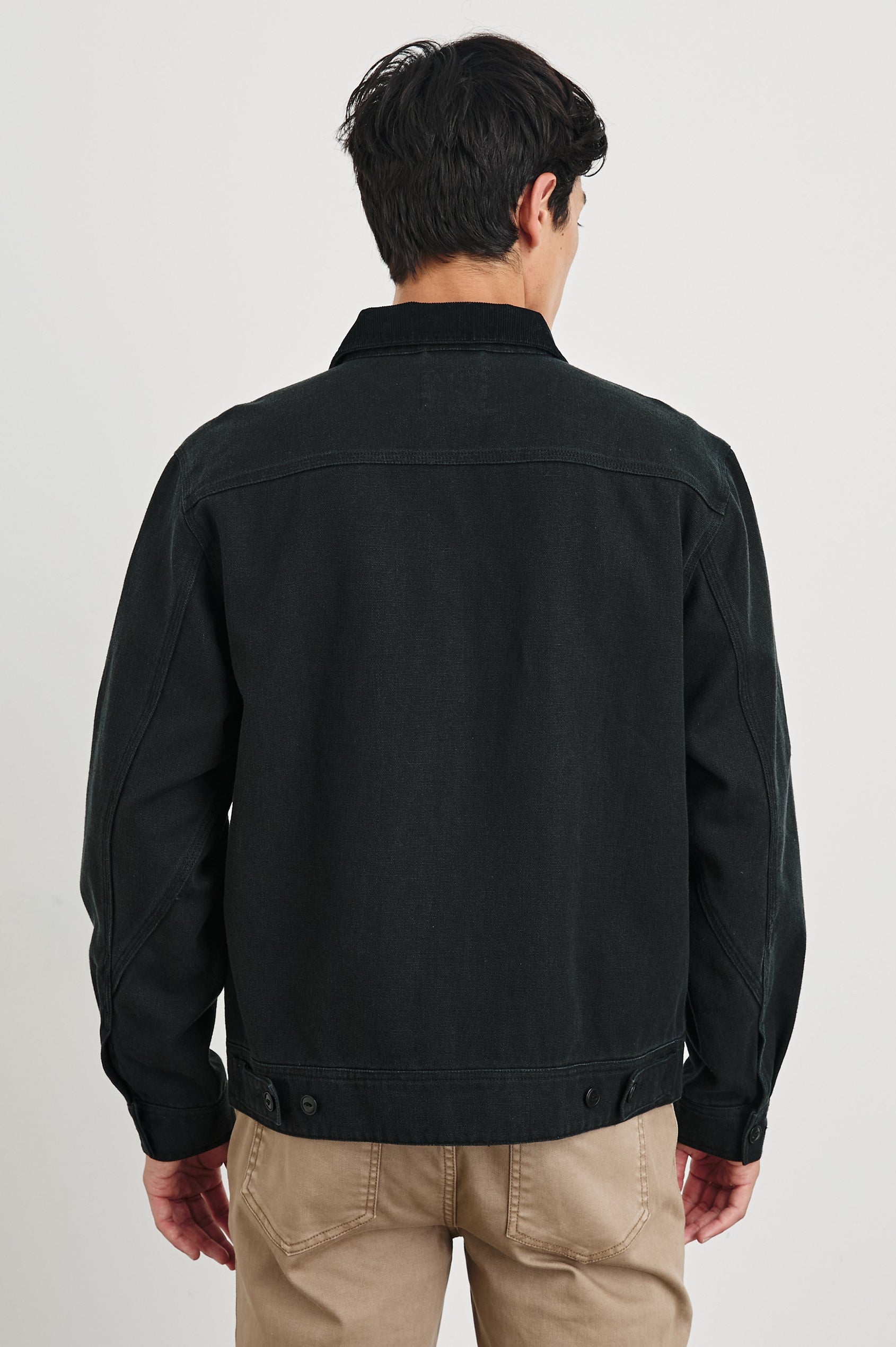 Ketter Zip Up Jacket with Two Curved Front Patch Pockets, a Diagonally Zippered Chest Patch Pocket and Adjustable Button Straps on the Hem in Raven Colorway - Back View Featured on Model