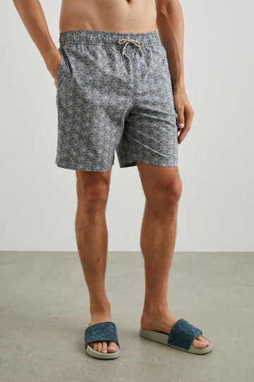 Kian Swim Shorts with an Elastic Drawstring Waistband, Two Front Pockets and a Back Button Flap Pocket in Tribal Batik Celestial Colorway, Geometric patten in Black, White and tan - Front View Featured on Model