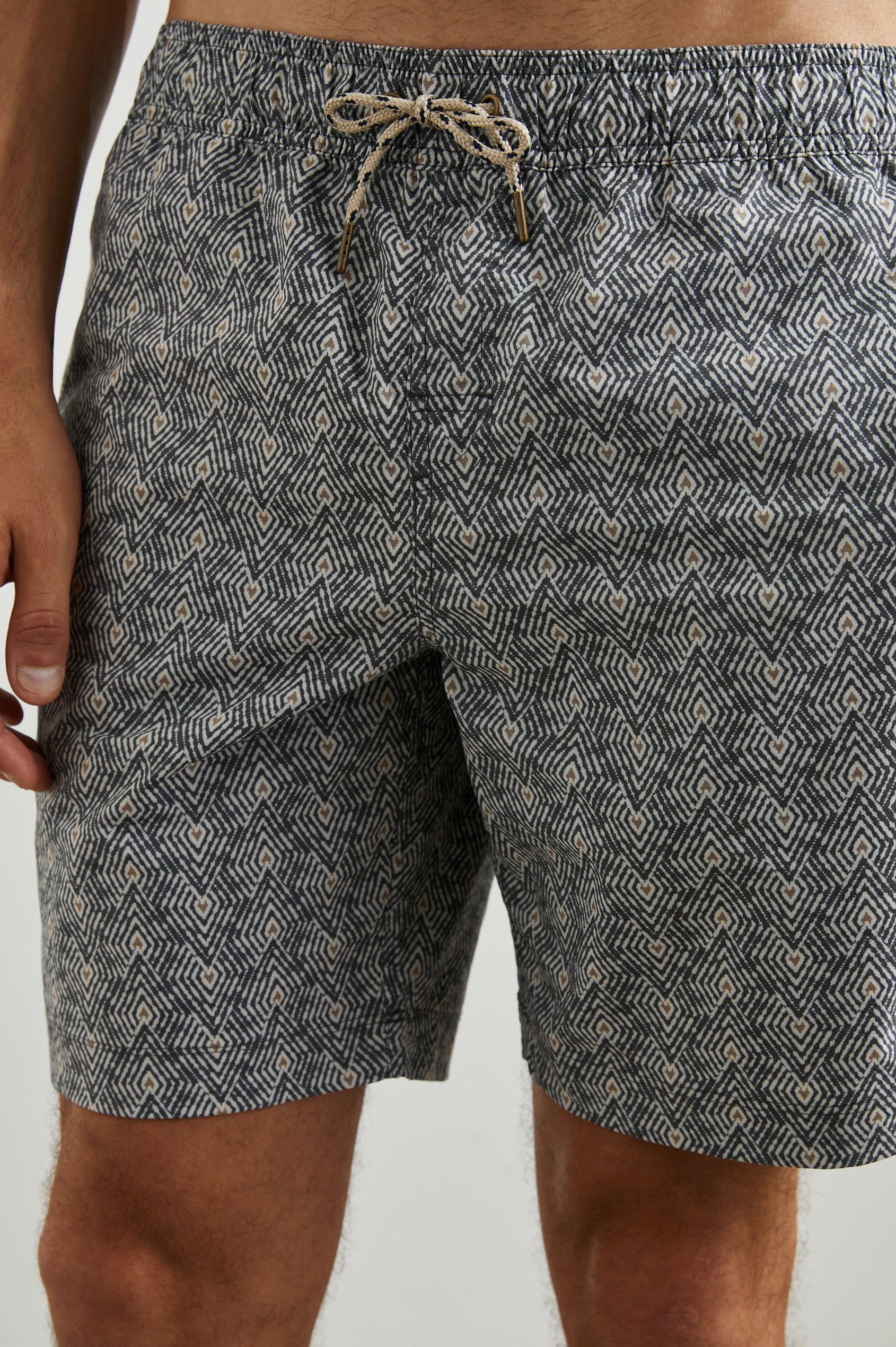 Kian Swim Shorts with an Elastic Drawstring Waistband, Two Front Pockets and a Back Button Flap Pocket in Tribal Batik Celestial Colorway, Geometric patten in Black, White and tan - Front View Featured on Model