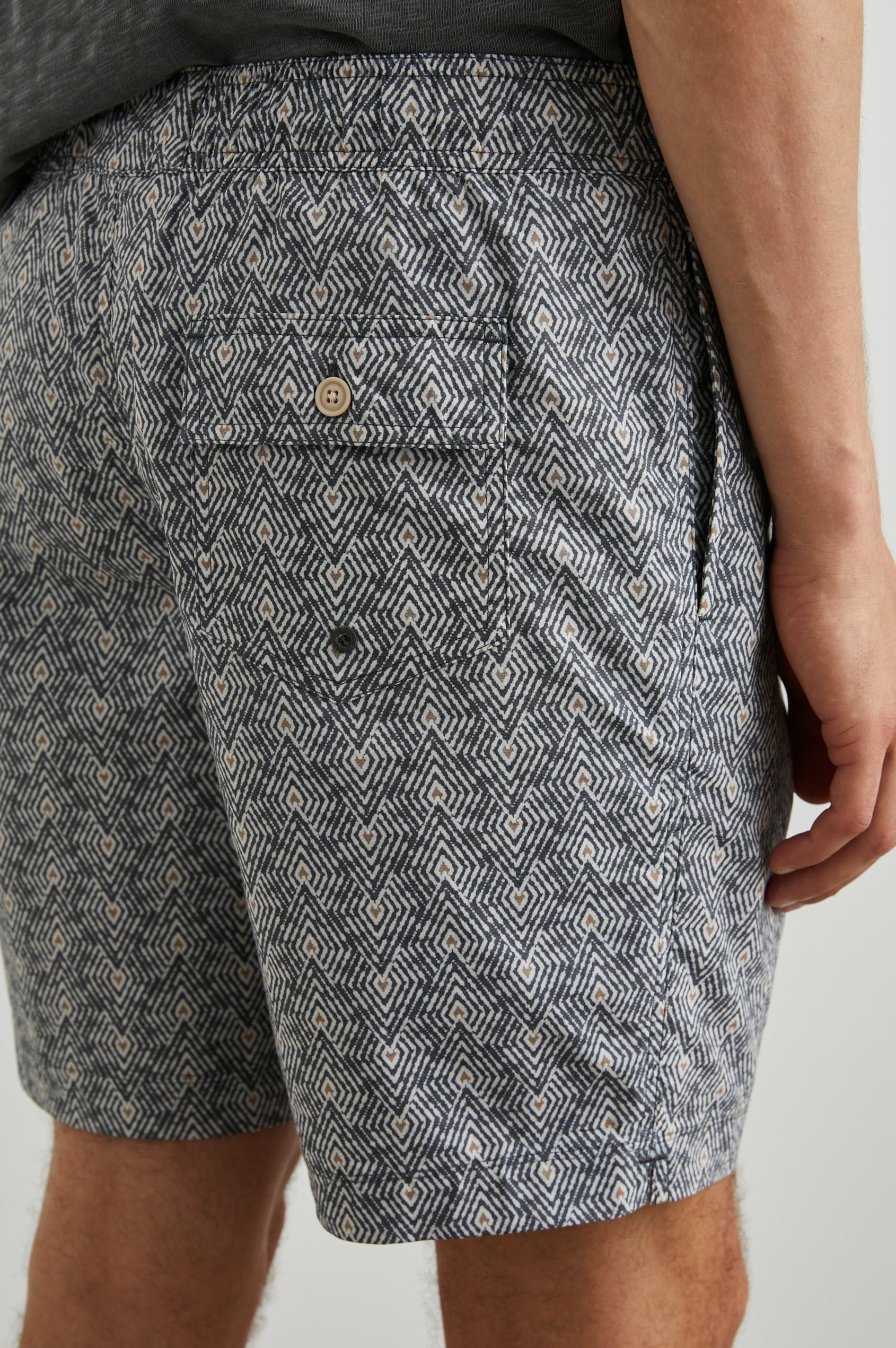 Kian Swim Shorts with an Elastic Drawstring Waistband, Two Front Pockets and a Back Button Flap Pocket in Tribal Batik Celestial Colorway, Geometric patten in Black, White and tan - Back View Featured on Model