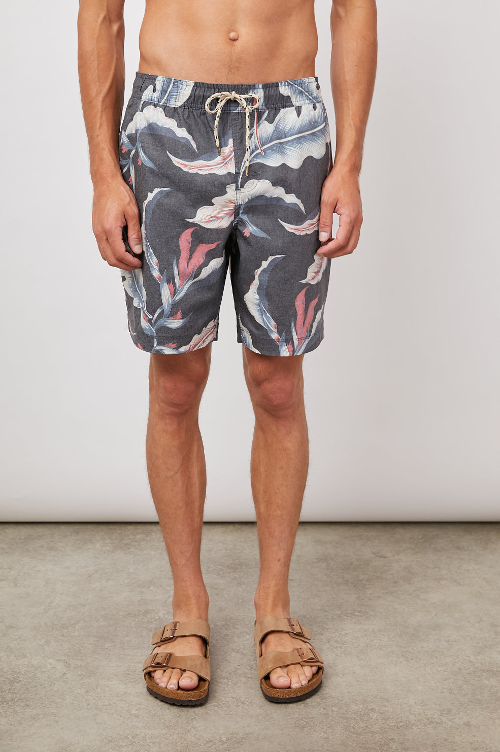 Kian Swim Shorts with an Elastic Drawstring Waistband, Two Front Pockets and a Back Button Flap Pocket in Paradise Nights Colorway, a Floral Print in Pinks, Blues and White on Black - Front View Featured on Model