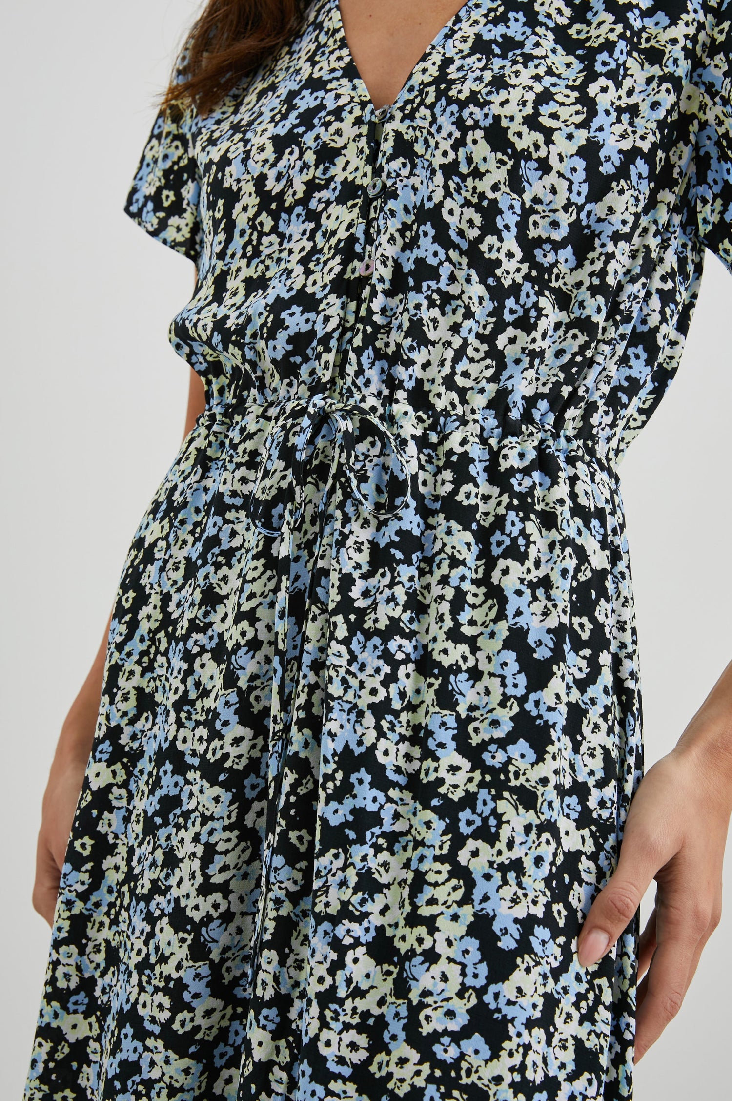 Kiki Short Sleeve Midi Dress with a V Neck, Buttons Down the Front Bodice, a Drawstring Waist and Ruffles at the Hem in Midnight Meadow Floral Colorway, Blue and Cream Flowers on Black - Front View Featured on Model 