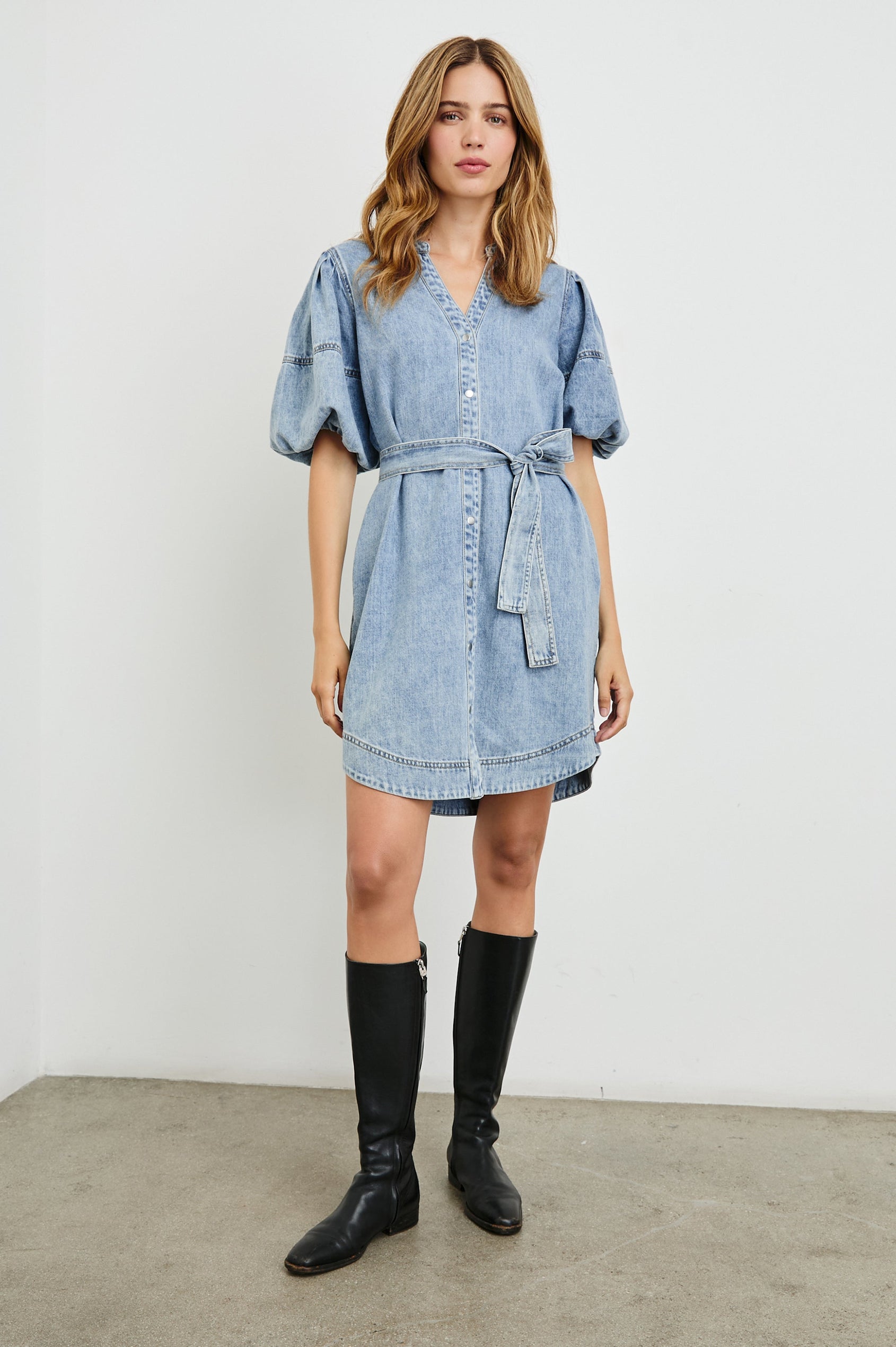 Kingsley Denim Mini Dress with Elbow-Length Puff Sleeves, a V Neck, Snaps Down the Front and a Fabric Tie Belt in Faded Indigo Colorway - Front Full Body View Featured on Model 