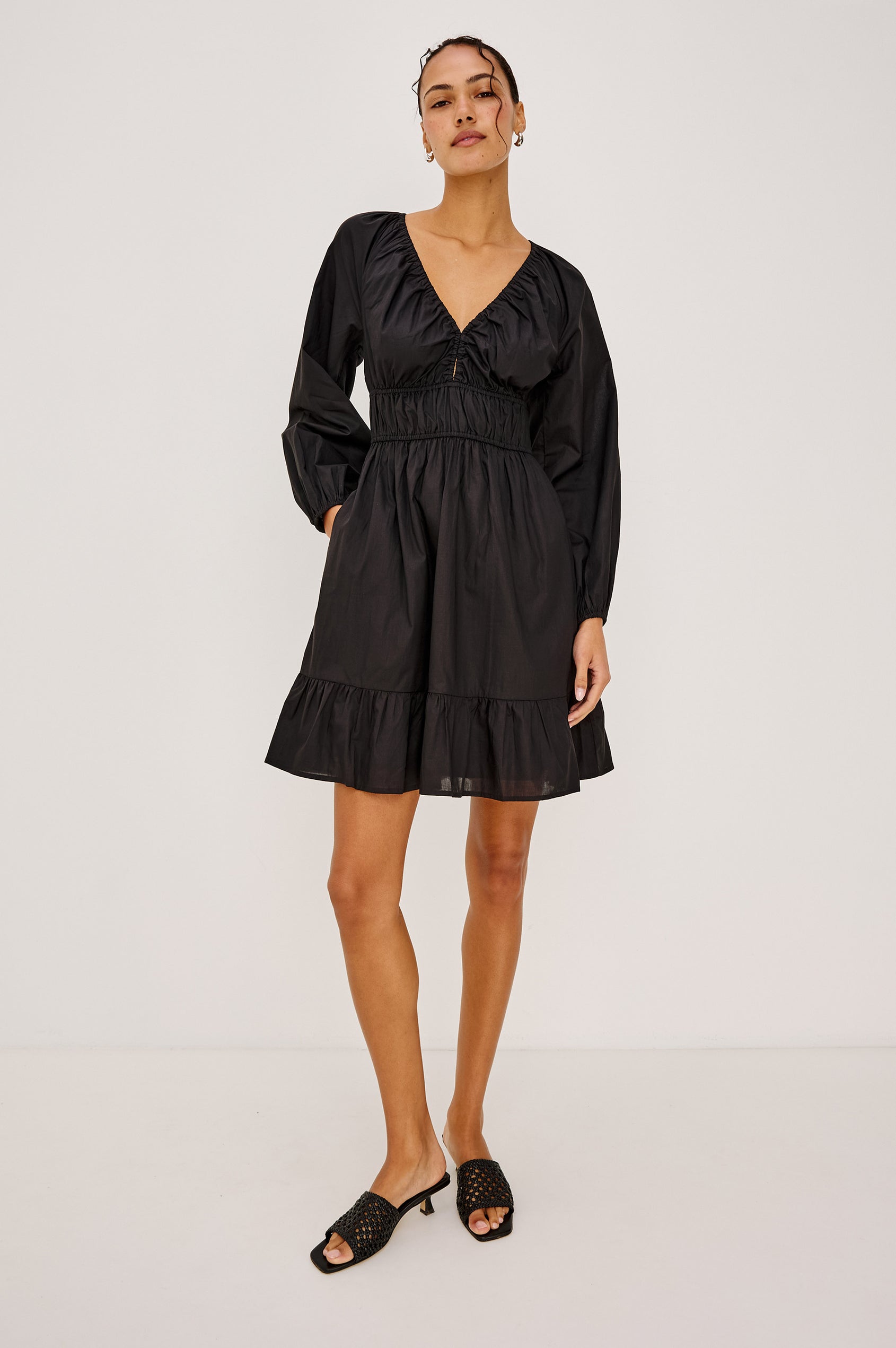 Krina Mini Dress in Cotton Poplin With Deep V-Neckline, Center Front Ties, Long Billowing Sleeves, and Tiered Hem in Black Colorway - Full Body Front View Featured on Model