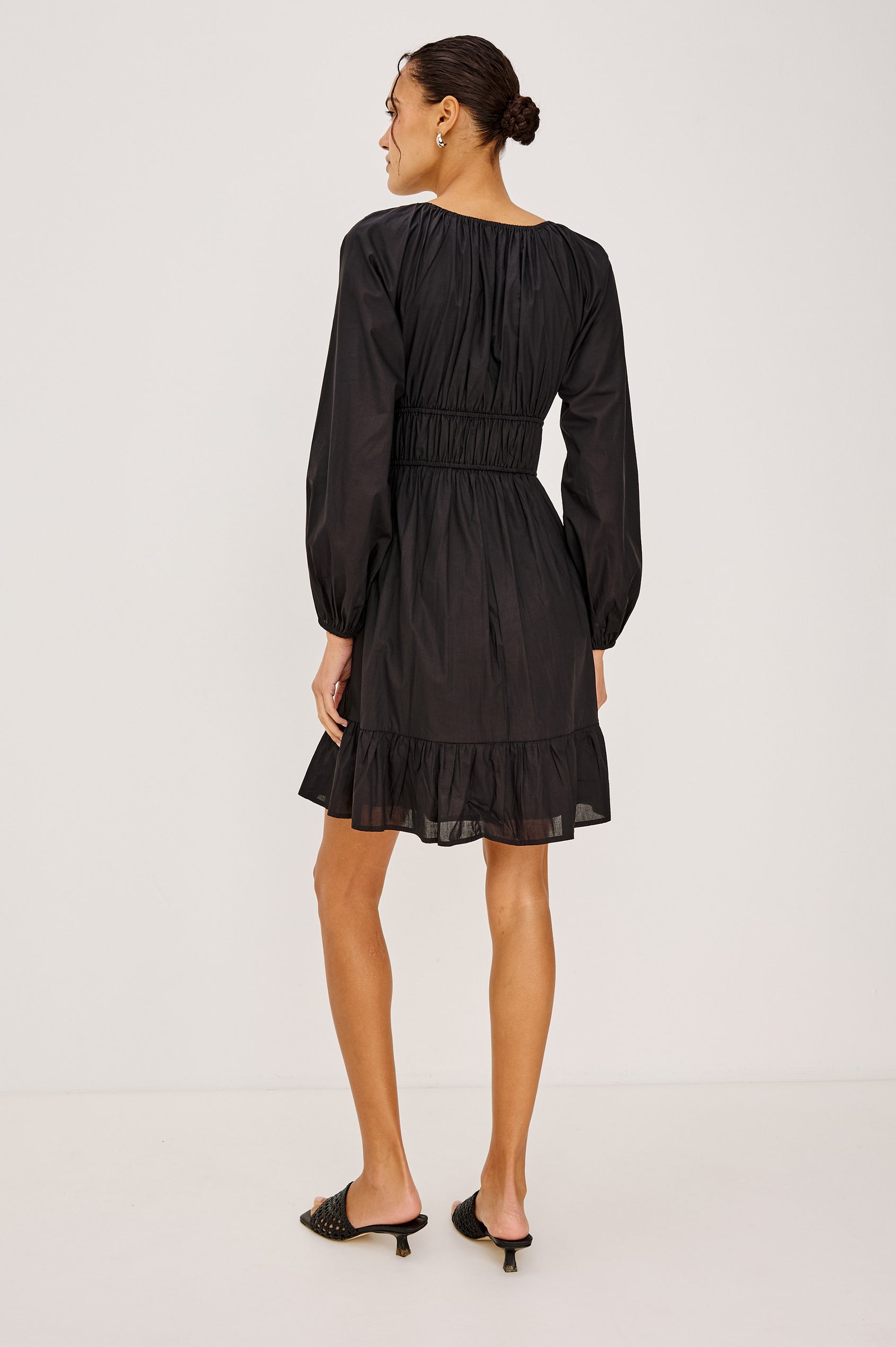 Krina Mini Dress in Cotton Poplin With Deep V-Neckline, Center Front Ties, Long Billowing Sleeves, and Tiered Hem in Black Colorway - Full Body Back View Featured on Model