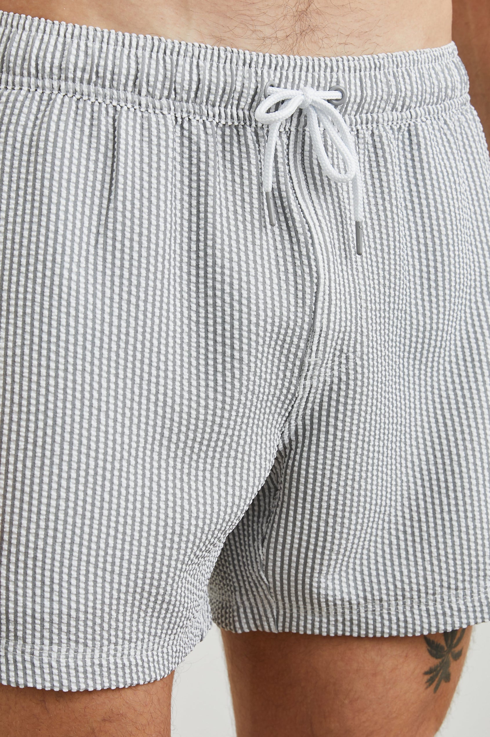La Brea Swim Shorts with a Drawstring Waist, Two Front Pockets and a Back Patch Pocket in Faded Seersucker Colorway, Grey and white thin vertical stripes - Front View Featured on Model