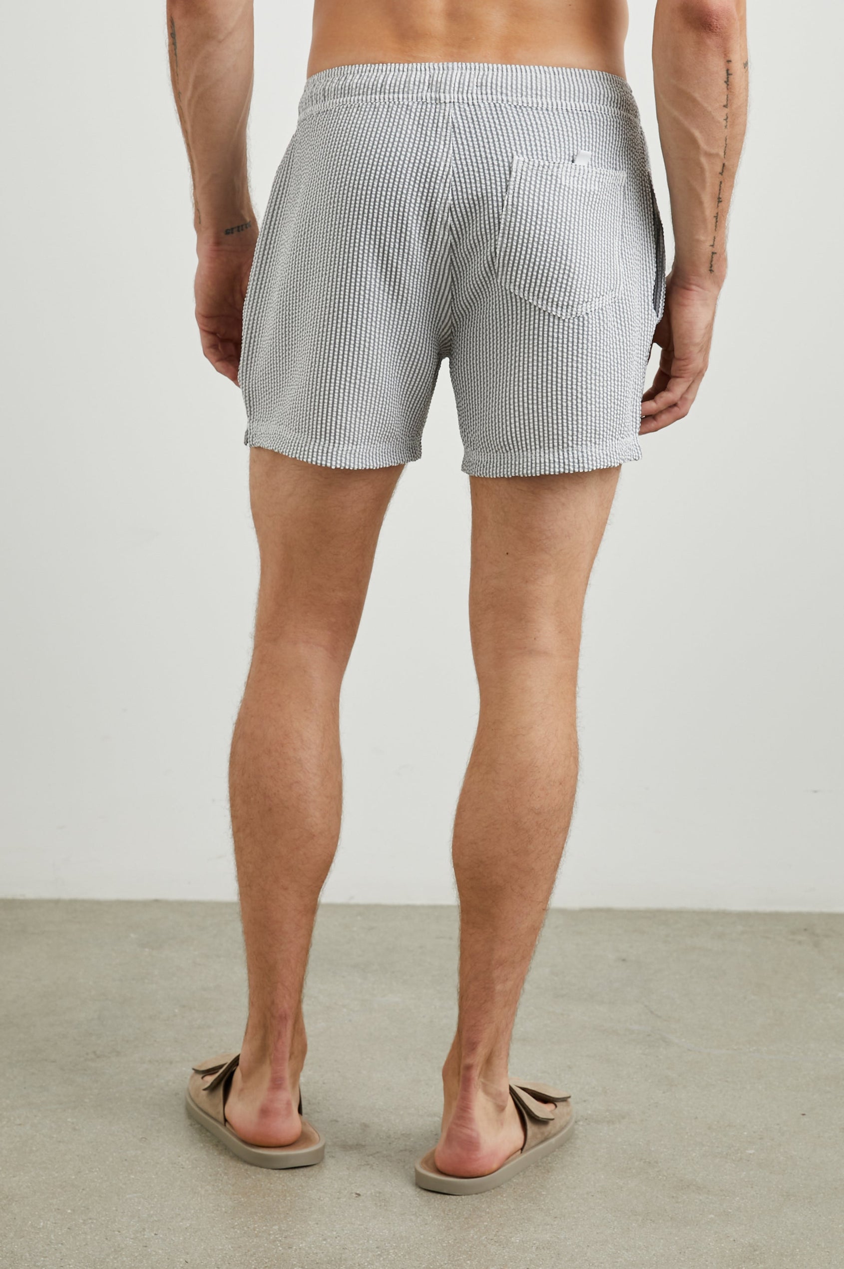 La Brea Swim Shorts with a Drawstring Waist, Two Front Pockets and a Back Patch Pocket in Faded Seersucker Colorway, Grey and white thin vertical stripes - Back View Featured on Model