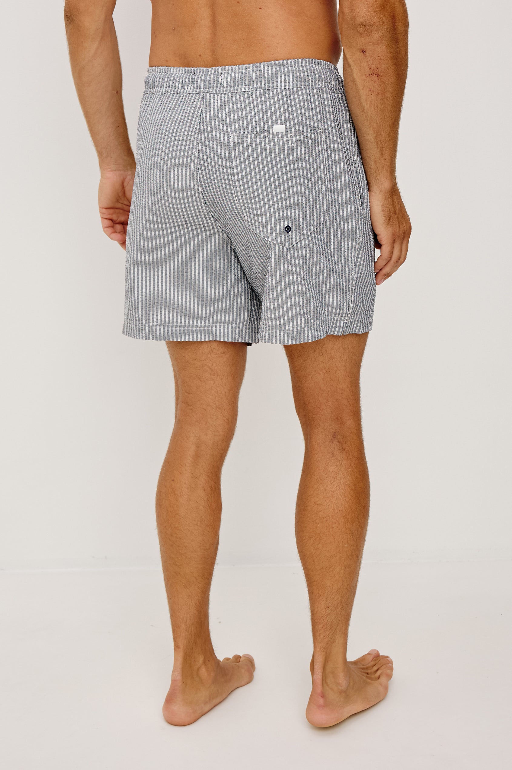La Brea Swim Short in Stretch Polyester Seersucker With Adjustable Drawstring Waist Ties in Navy Deck Stripe Colorway - Lower Body Back View Featured on Model