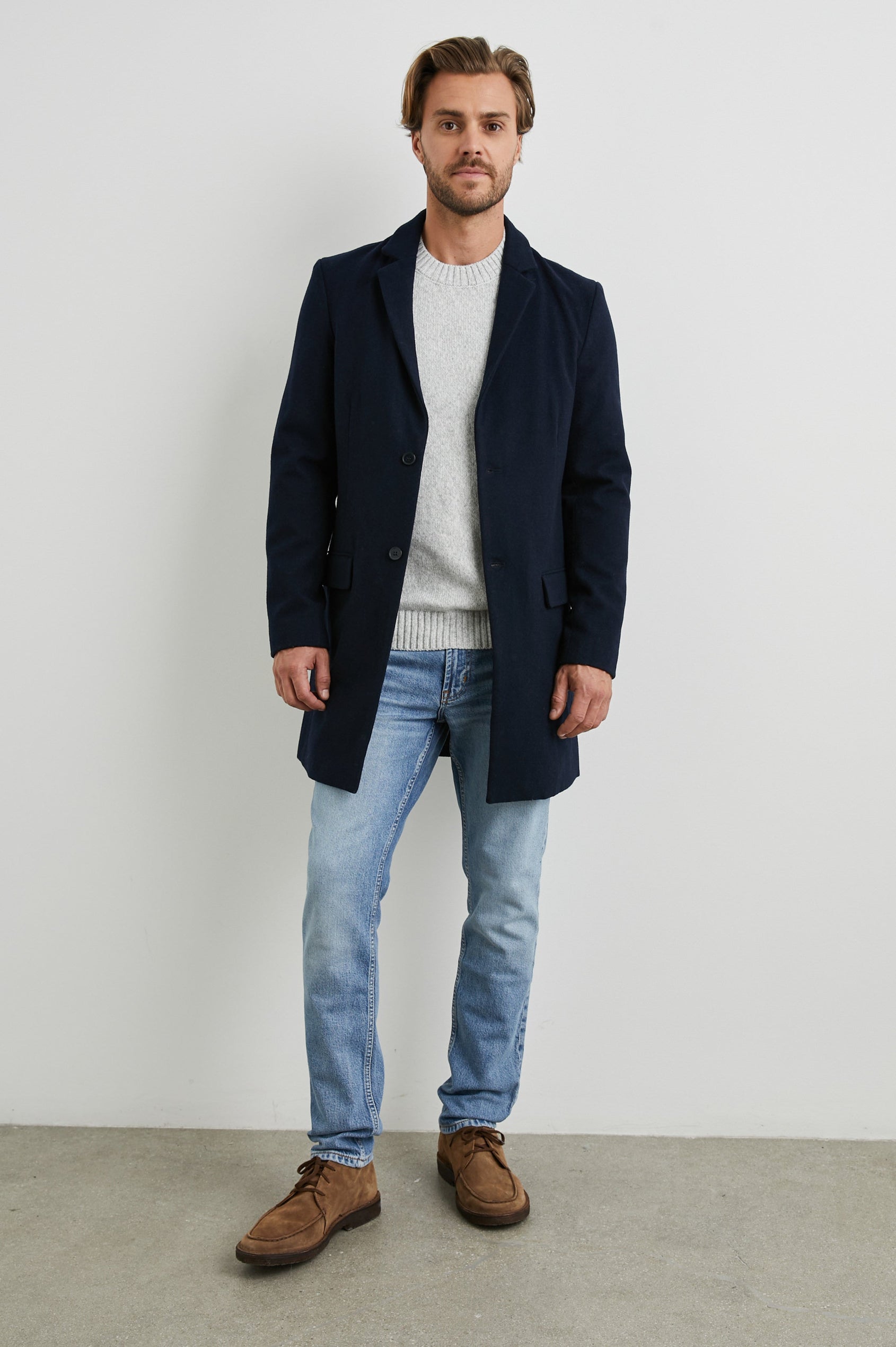 Lark Thigh-Length Coat with Two Button Closure, Notched Lapels, and Two Front Flap Pockets in Navy Colorway - Front Full Body View Featured on Model