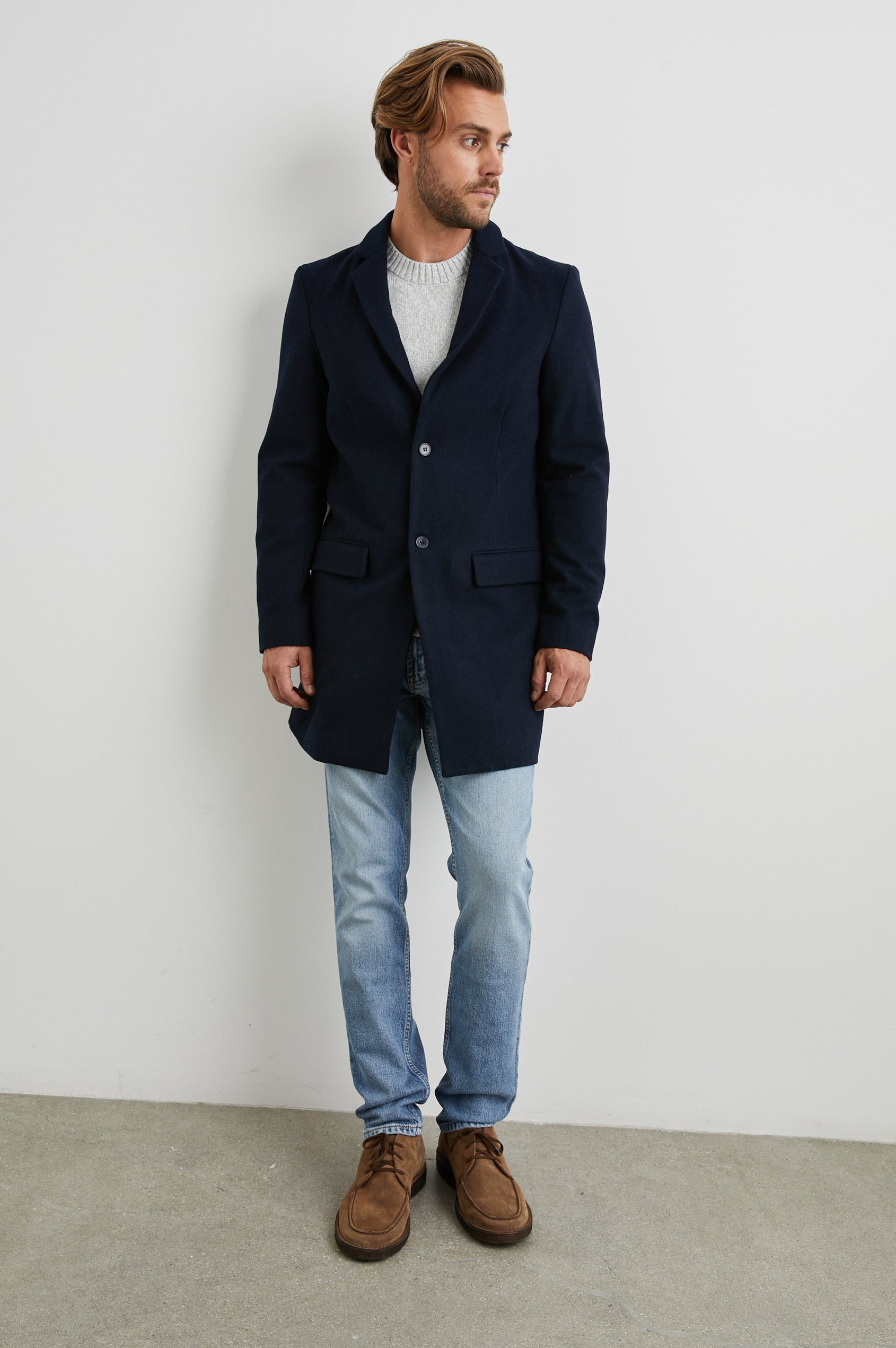 Lark Thigh-Length Coat with Two Button Closure, Notched Lapels, and Two Front Flap Pockets in Navy Colorway - Front Full Body View Featured on Model