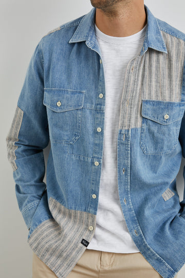 Larsen Long-Sleeve Button Up with Two Chest Button Flap Pockets in Medium Indigo Patchwork Colorway, Denim Patches and Vertical Stripes in Grey and White - Front Unbuttoned View Featured on Model