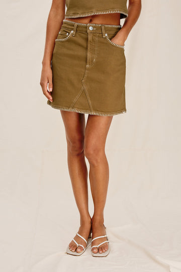 Laurel 5-Pocket Colored Denim Mini Skirt With Blanket Stitch Along All Edges in Safari Embroidered. Front View Shown on Model.