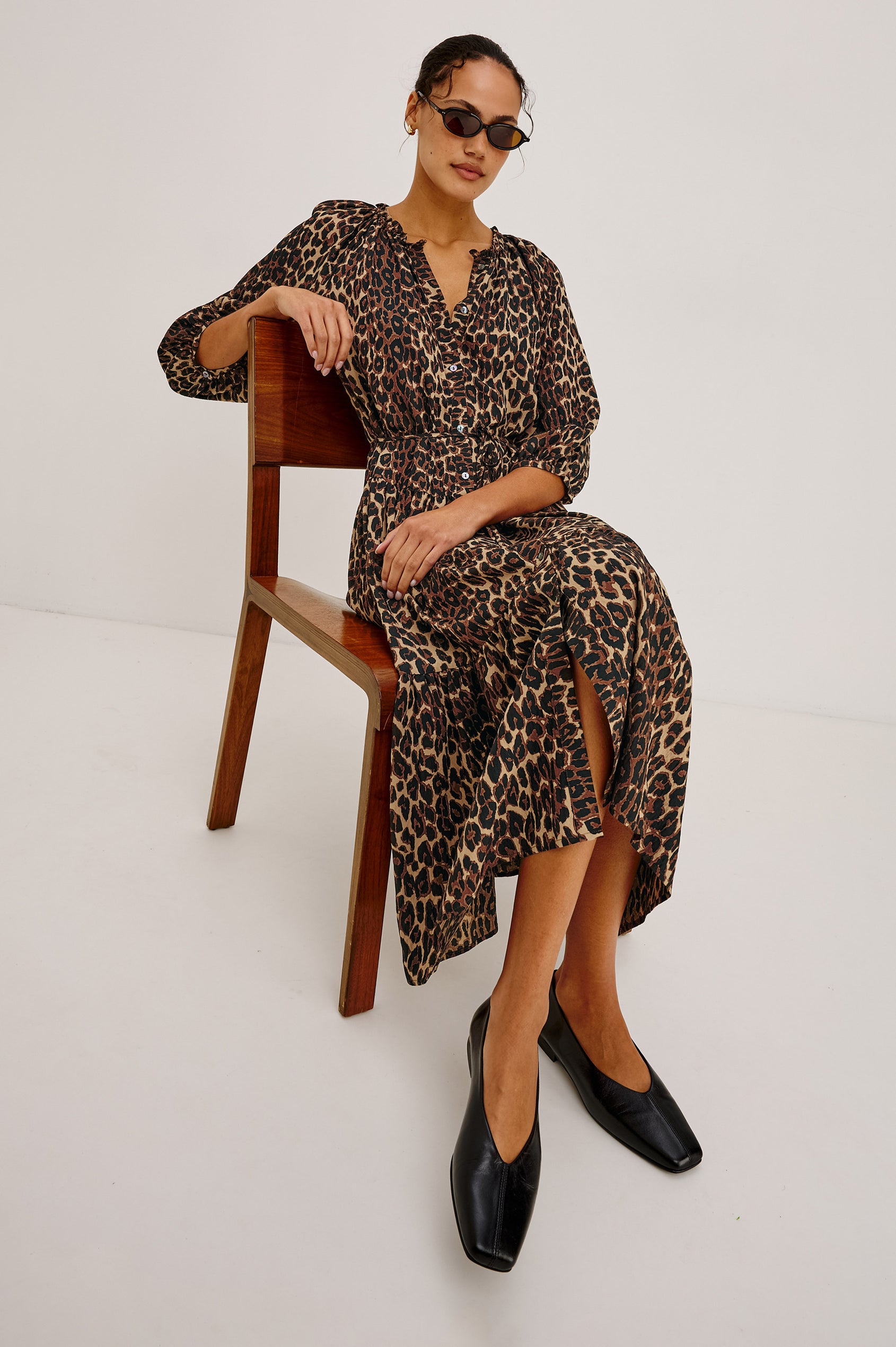 Leanne Maxi Dress in Crinkle Poplin With Loose Swing Fit, Ruffle Trim Peasant Neckline, Long Balloon Sleeves, Front Buttons, and Single Tier in Brown Nala Colorway - Full Body View Featured on Model Sitting