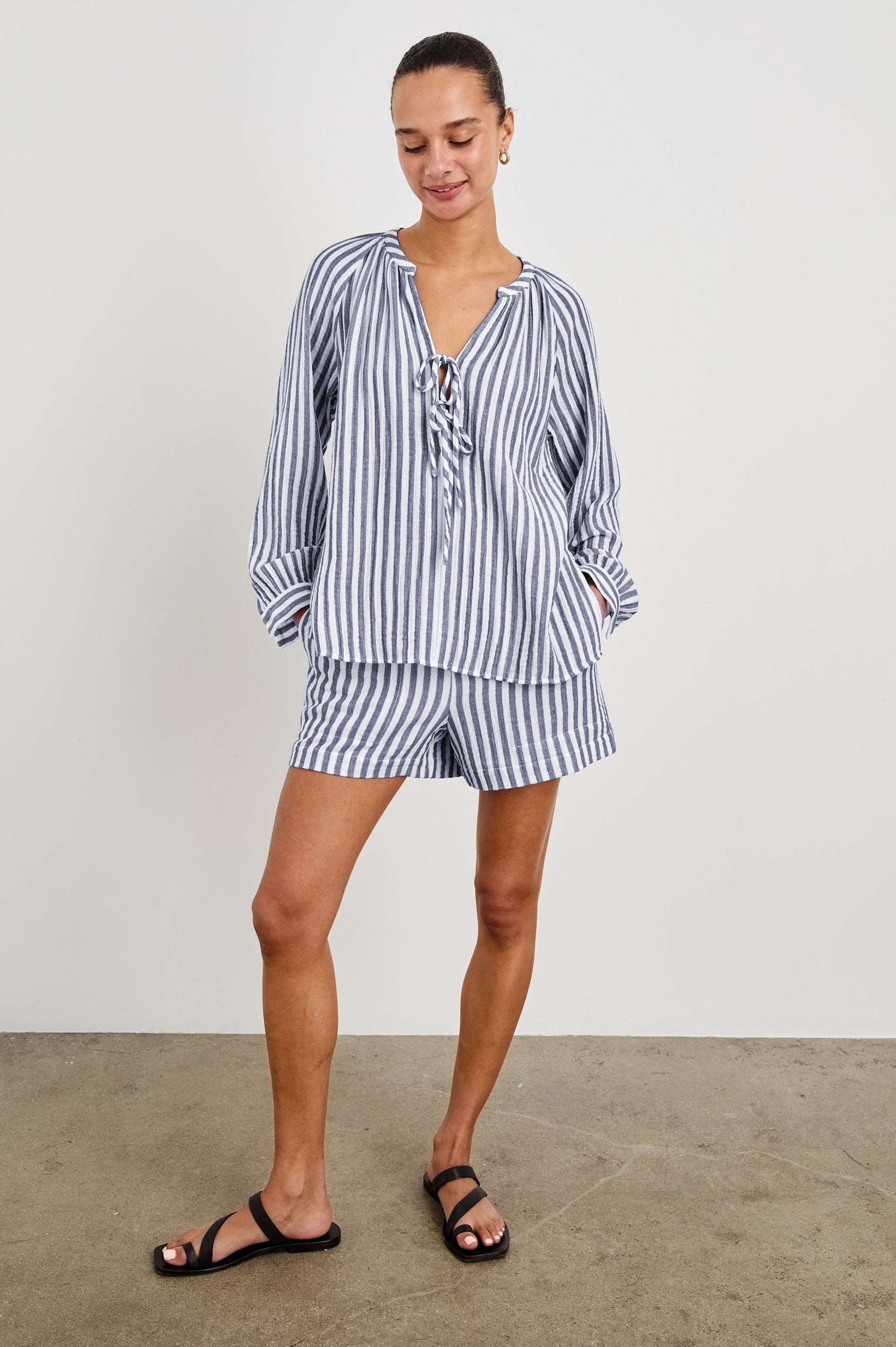 Model is wearing our Leighton Short featuring blue and white vertical stripes. High rise, lined, with a smocked elastic waistband. Styled with matching Brielle Top. 