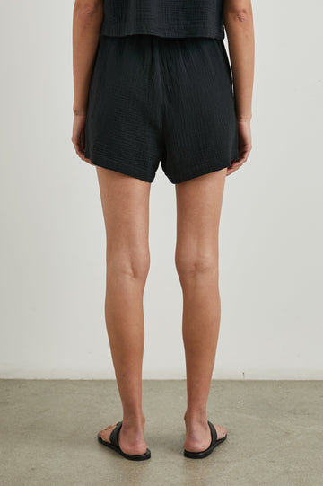 Leighton Shorts with Textured Fabric, a Smocked Elastic Waist, and Large Front Pockets in Black Colorway - Back View Featured on Model
