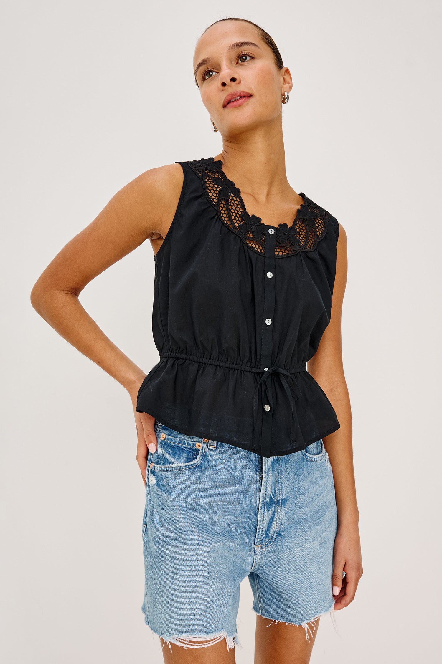 Leilani Top in Lightweight Beach Cotton With Scoop Neckline, Lattice Embroidery, Front Buttons, Relaxed Fit, and Adjustable Waist Ties in Black Colorway - Upper Body Front View Featured on Model