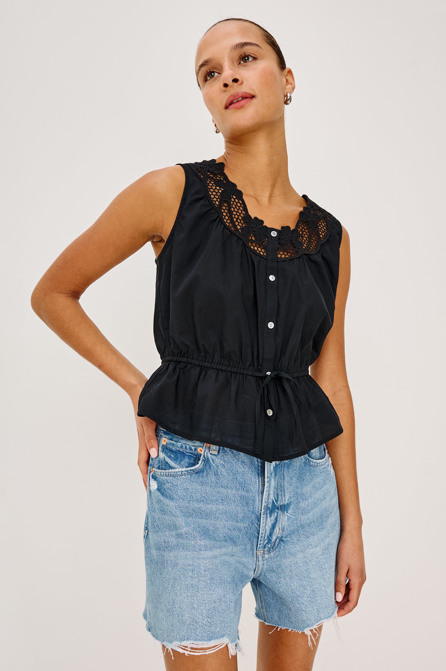 Leilani Top in Lightweight Beach Cotton With Scoop Neckline, Lattice Embroidery, Front Buttons, Relaxed Fit, and Adjustable Waist Ties in Black Colorway - Upper Body Front View Featured on Model