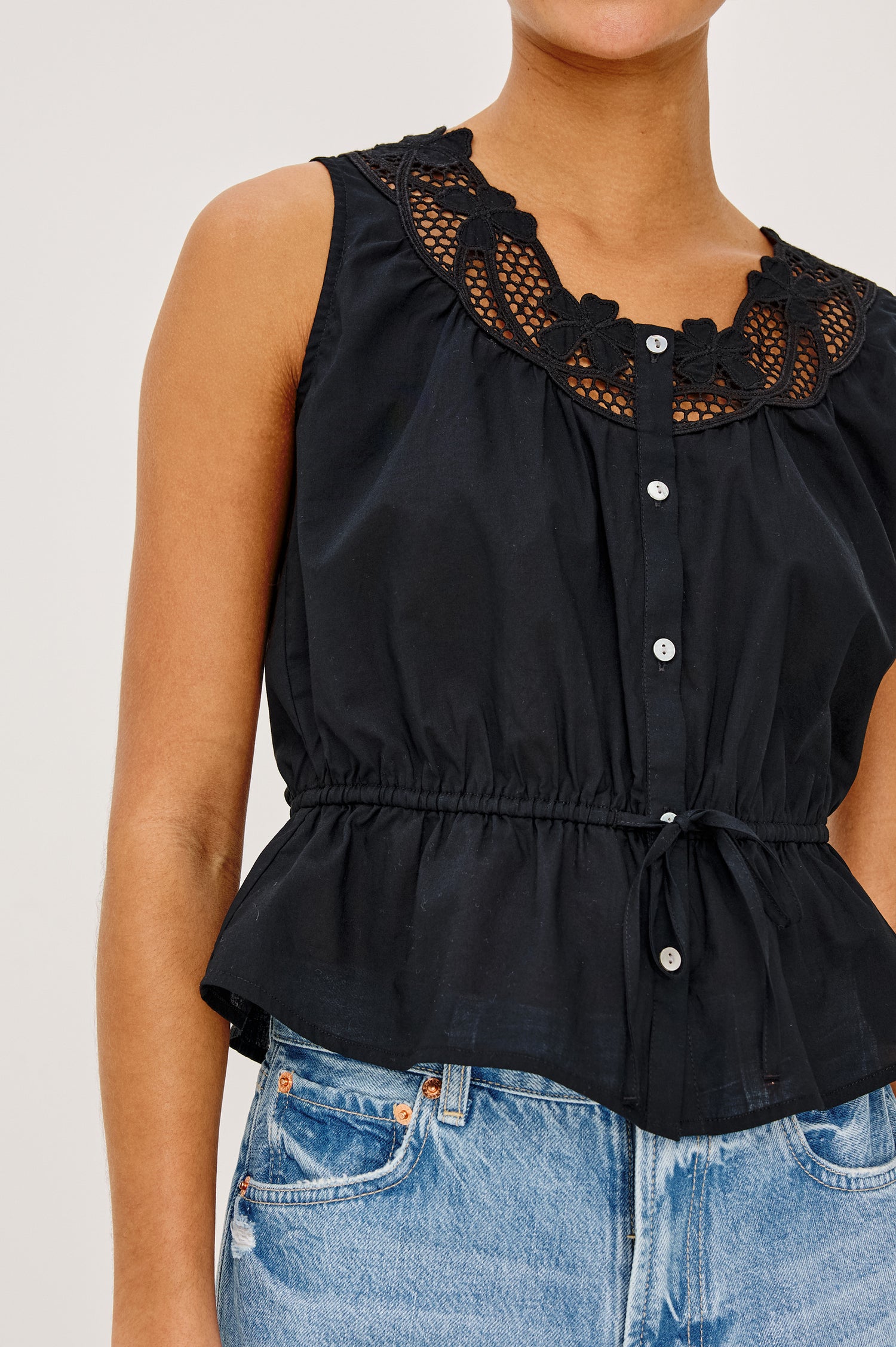 Leilani Top in Lightweight Beach Cotton With Scoop Neckline, Lattice Embroidery, Front Buttons, Relaxed Fit, and Adjustable Waist Ties in Black Colorway - Upper Body Close Up Front View Featured on Model