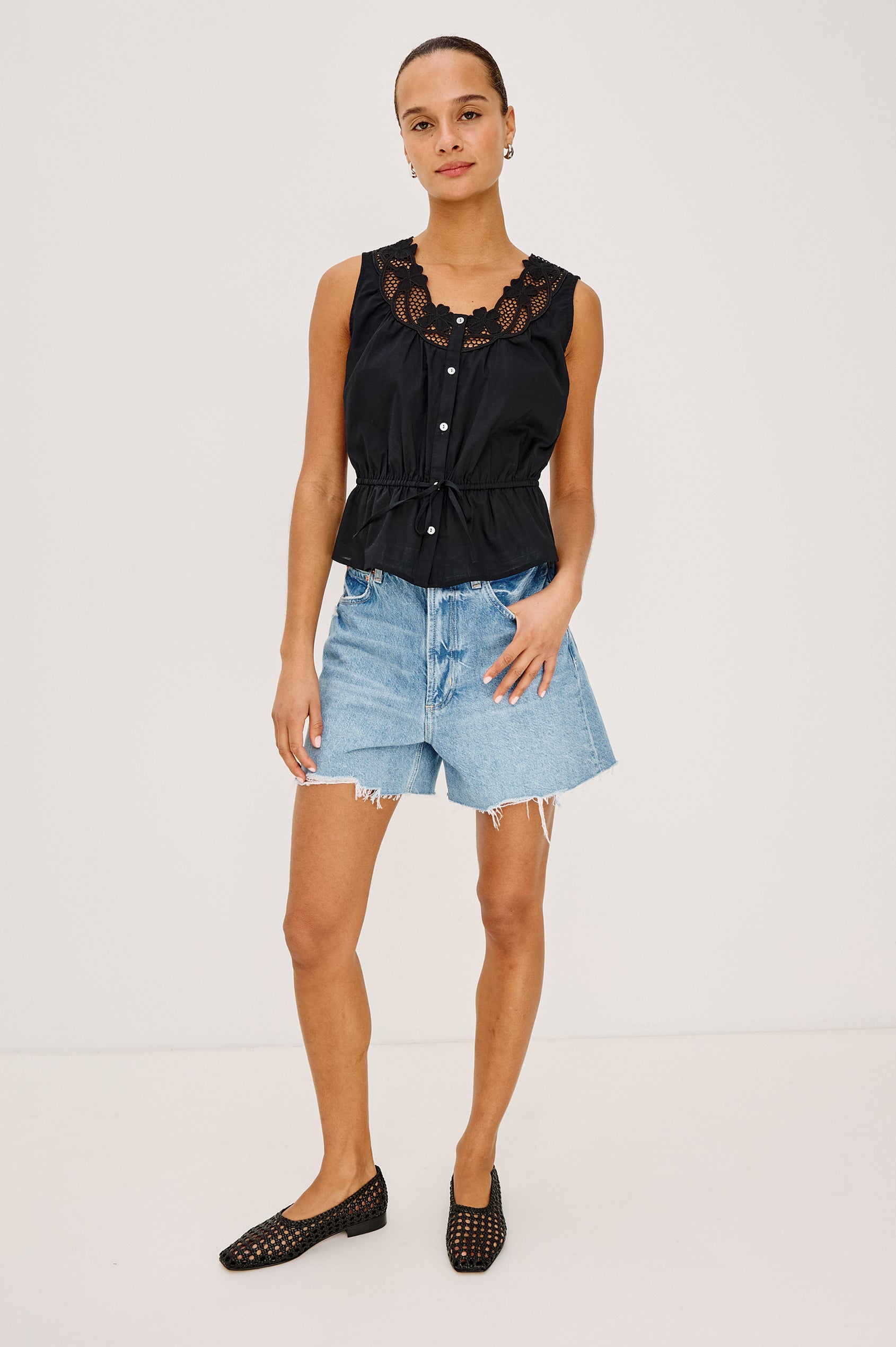 Leilani Top in Lightweight Beach Cotton With Scoop Neckline, Lattice Embroidery, Front Buttons, Relaxed Fit, and Adjustable Waist Ties in Black Colorway - Full Body Front View Featured on Model