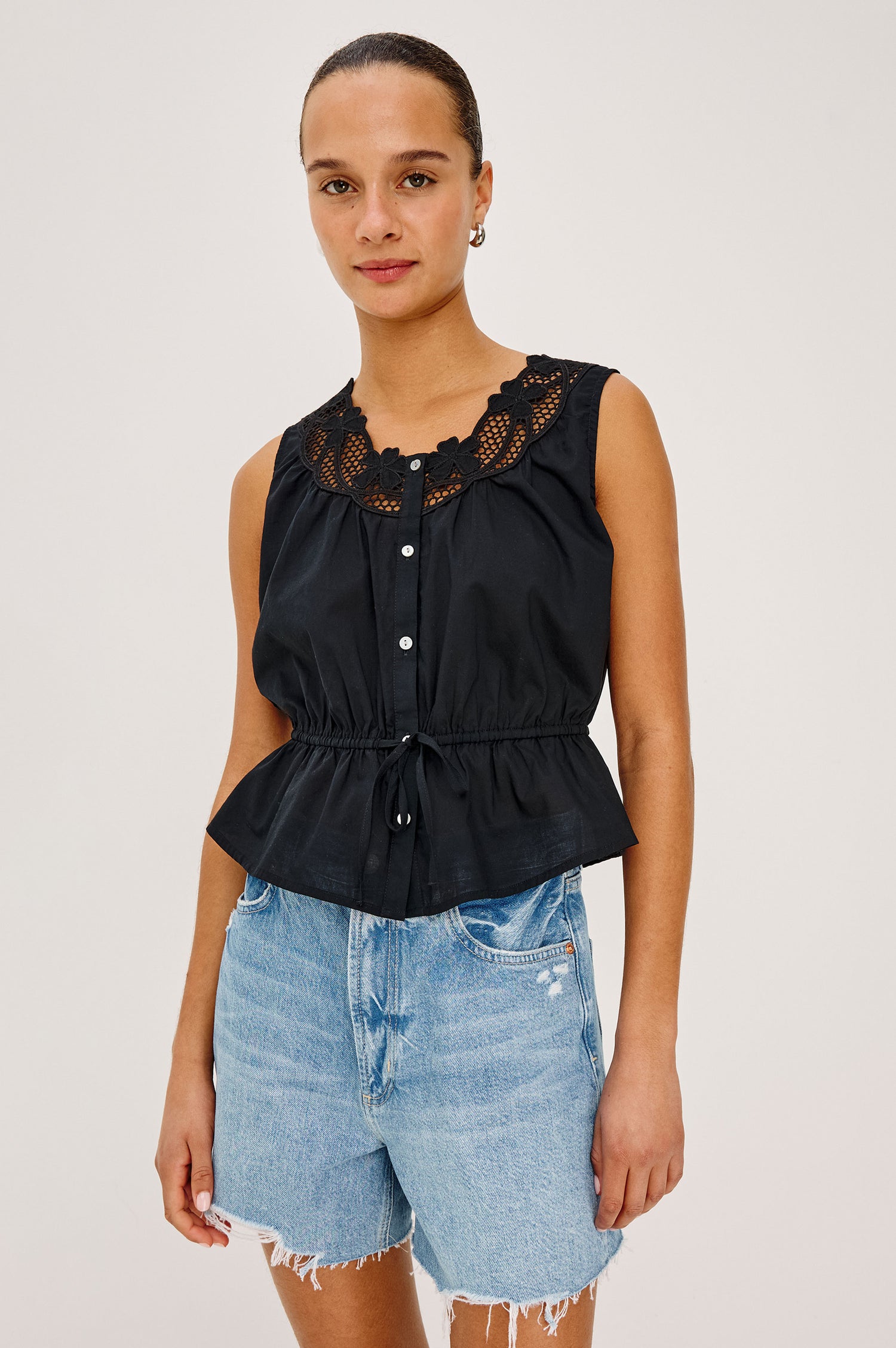 Leilani Top in Lightweight Beach Cotton With Scoop Neckline, Lattice Embroidery, Front Buttons, Relaxed Fit, and Adjustable Waist Ties in Black Colorway - Upper Body Front View Featured on Model