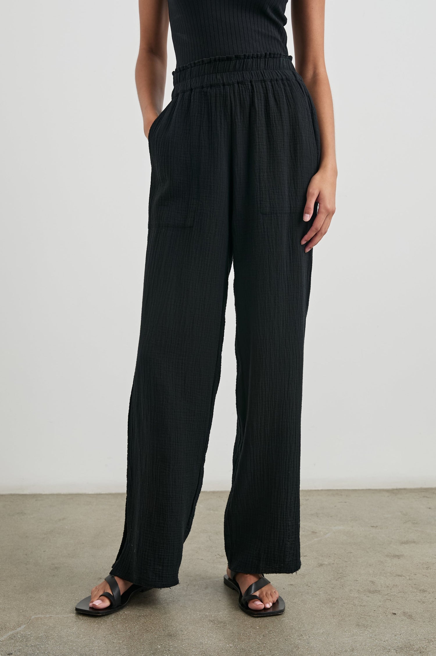Leon Pant with a Smocked Waistband, Short Side Slits on Outer Leg and Two Front Seam Pockets in Black Colorway - Front View Featured on Model