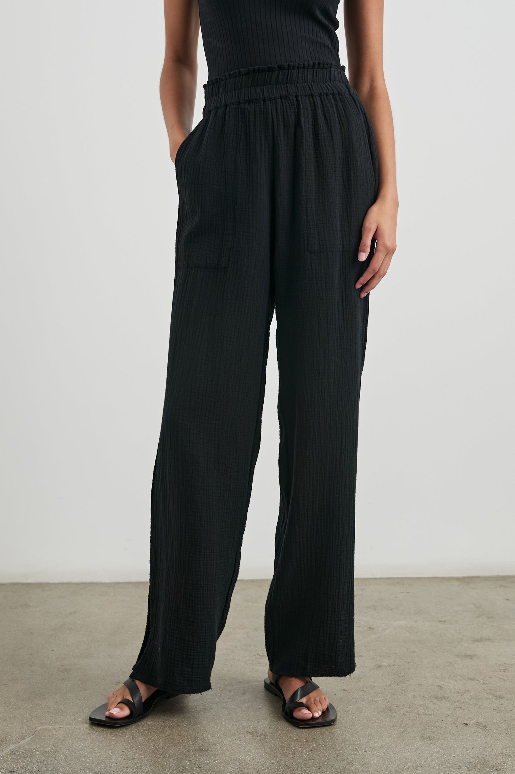 Leon Pant with a Smocked Waistband, Short Side Slits on Outer Leg and Two Front Seam Pockets in Black Colorway - Front View Featured on Model