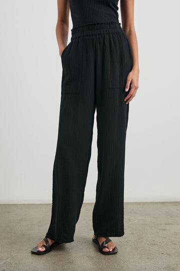 Leon Pant with a Smocked Waistband, Short Side Slits on Outer Leg and Two Front Seam Pockets in Black Colorway - Front View Featured on Model