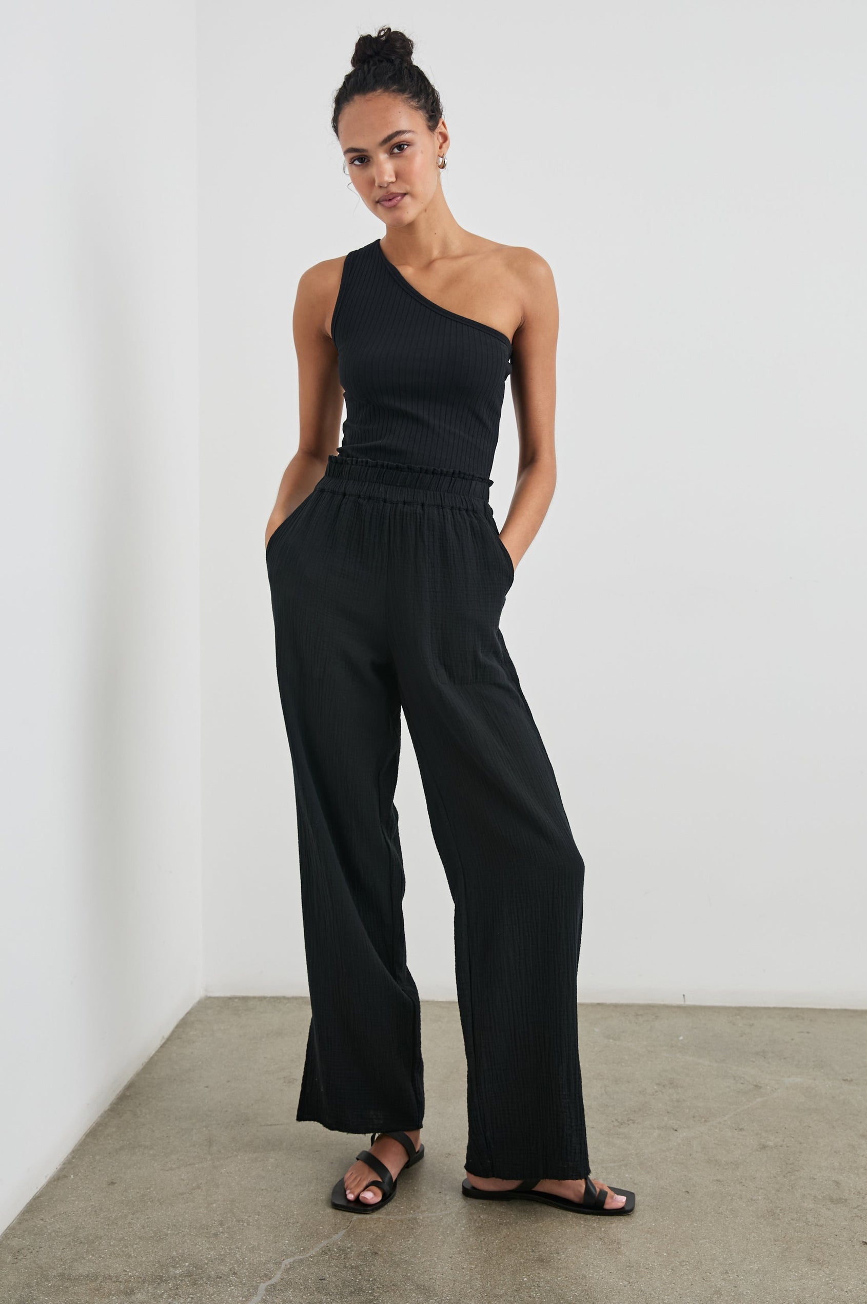Leon Pant with a Smocked Waistband, Short Side Slits on Outer Leg and Two Front Seam Pockets in Black Colorway - Front Full Body View Featured on Model