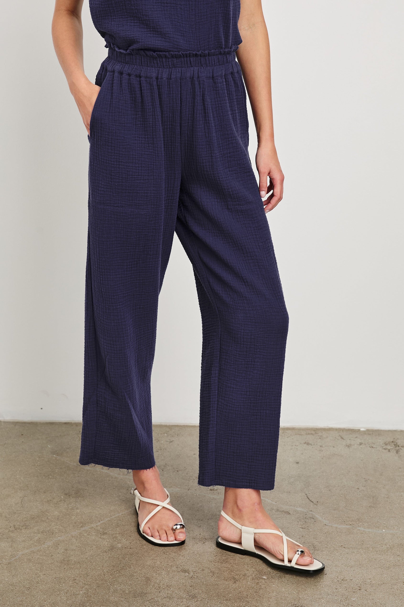 Leon Crop Cotton Gauze Pant With Hemline Slit And Elastic Waist In Colorway Admiral Blue - Front View Featured On Model Hand In Pocket