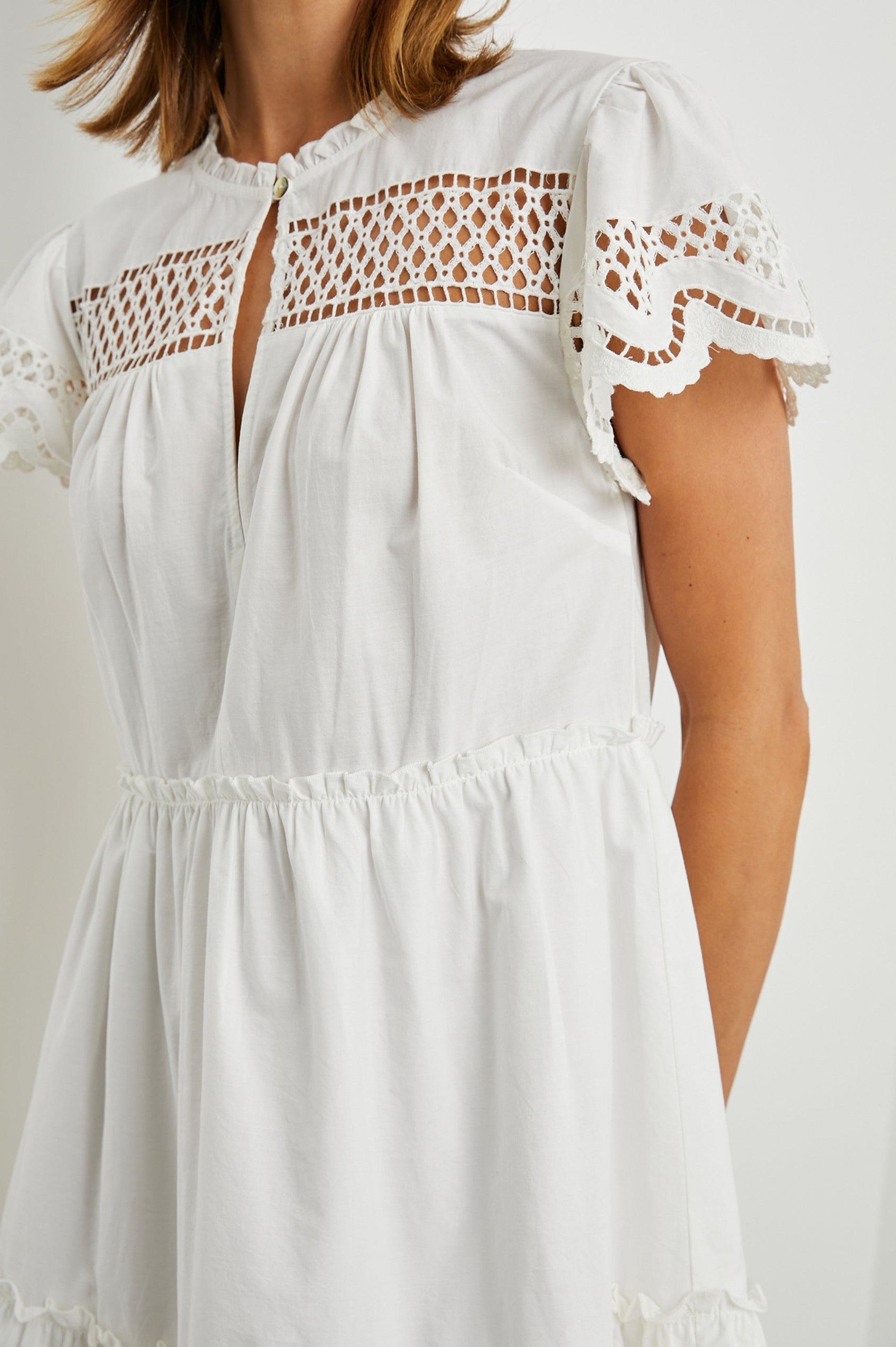 Lettie Short Sleeve Mini Dress with a Button Keyhole Neckline, a Tiered Skirt, and an Eyelet Design on the Yoke, Sleeves and Hem in White Colorway - Front View Featured on Model 
