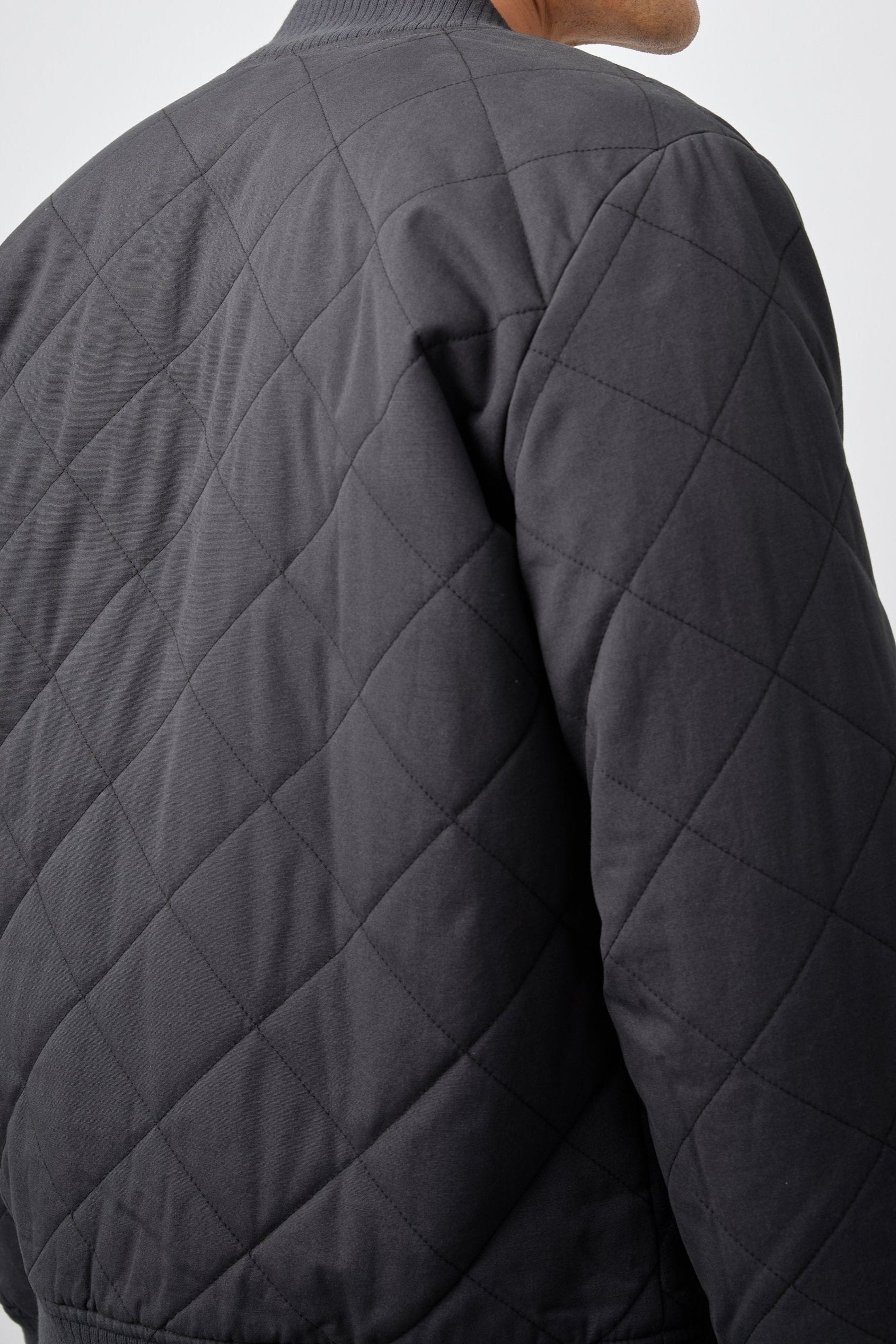 Peninsula Jacket with Zip Closure, Two Front Pockets, an Inner Zippered Pocket, a Quilted Pattern and Ribbed Trim in Washed Black Colorway - Back View Featured on Model